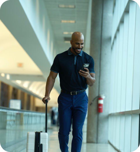 Traveller walking through an airport while checking his phone