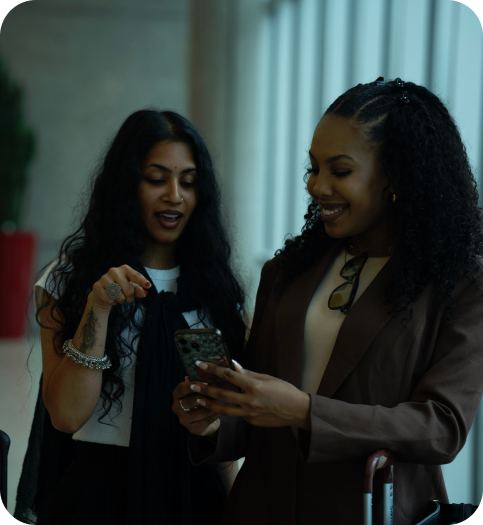 Two friends looking at a phone together while travelling