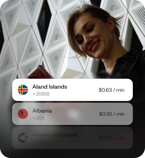 Woman smiling in a hotel lobby holding her phone and a coffee