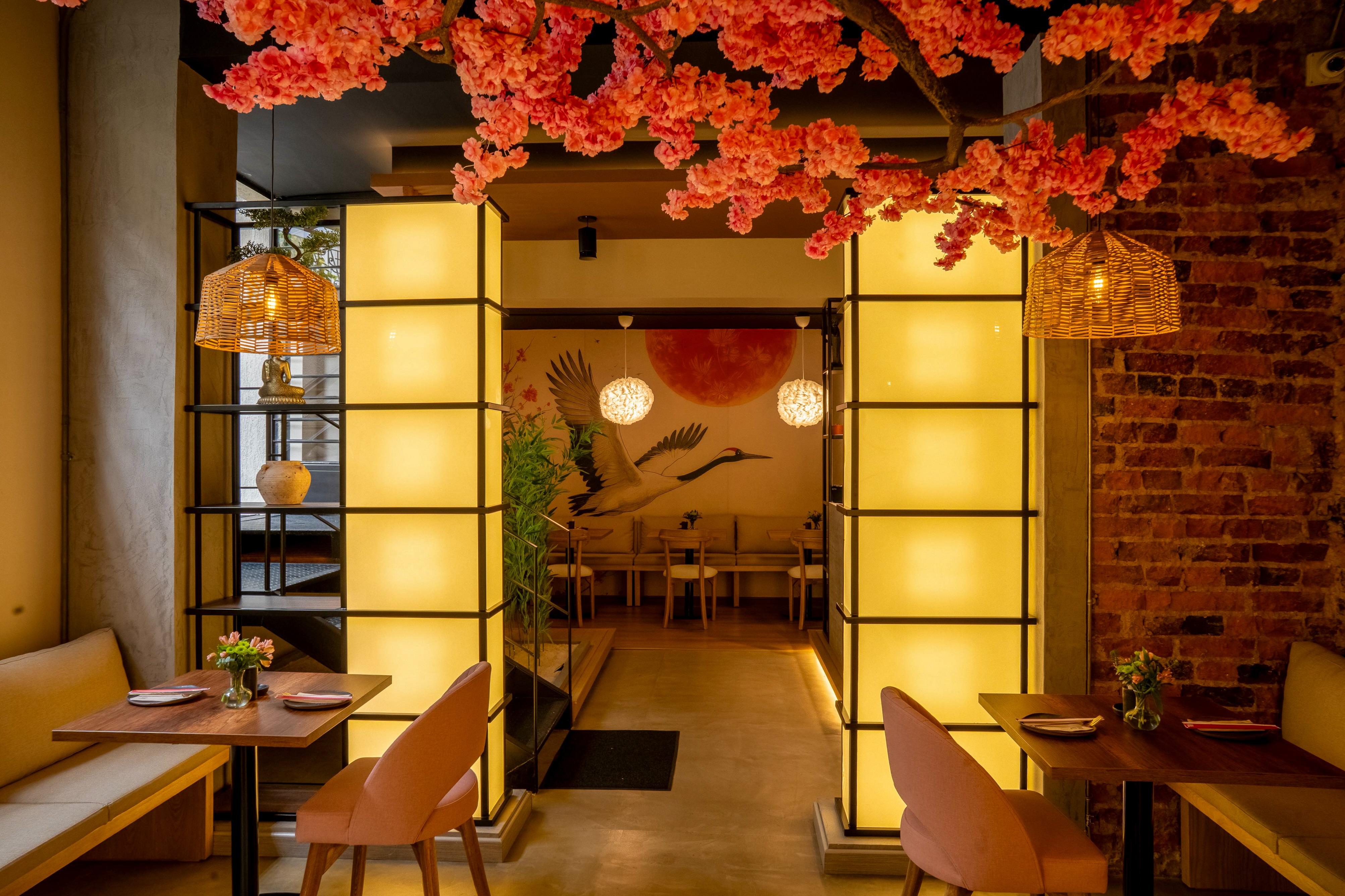 Interior of Quinto Cocina restaurant in Bogotá with warm lighting, cherry blossom decor, and Spottune Omni Cord speakers discreetly integrated into the ceiling.