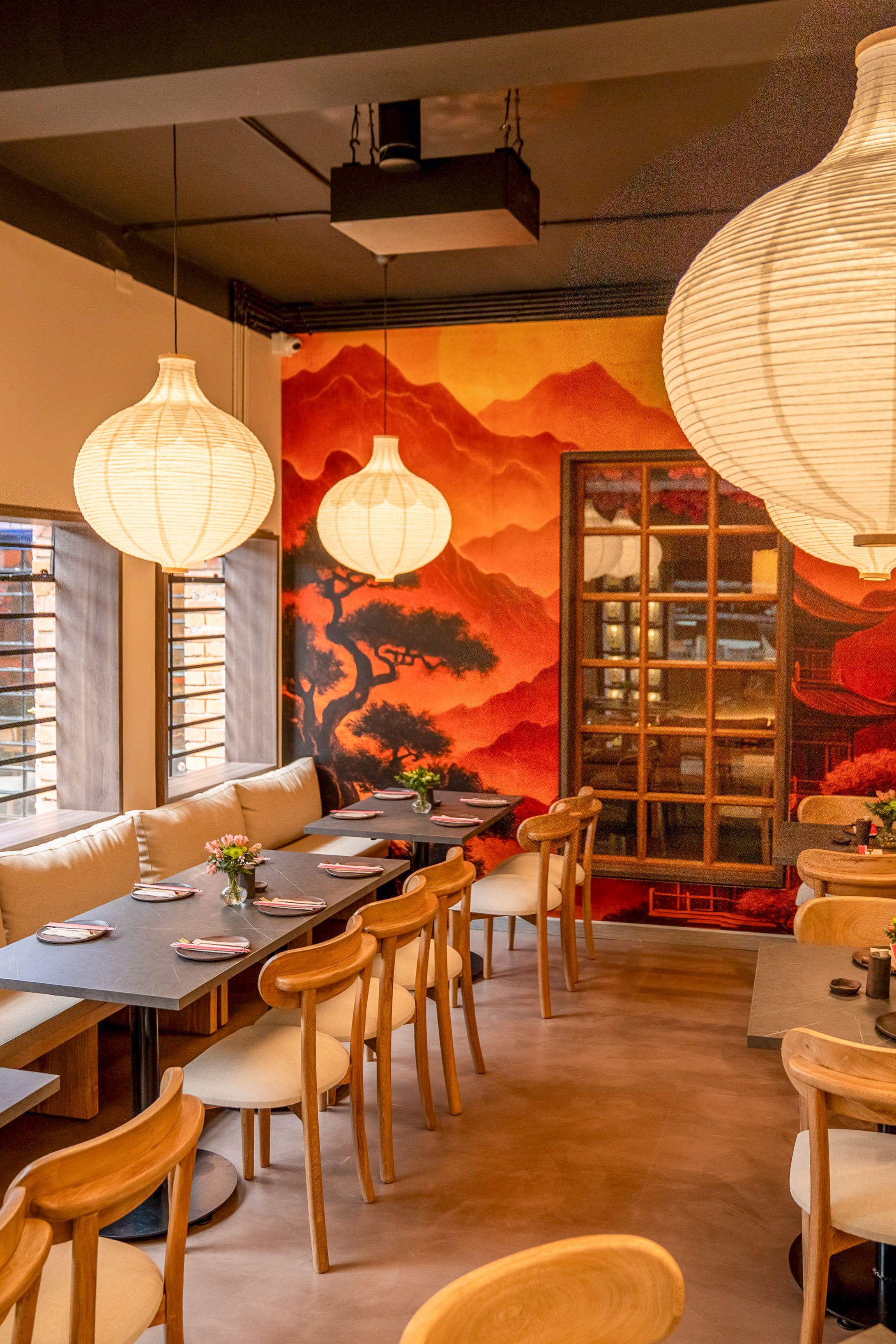 Dining area at Quinto Cocina in Bogotá featuring warm lighting, Japanese-inspired wall art, and a discreetly installed Spottune Sub for balanced restaurant audio.