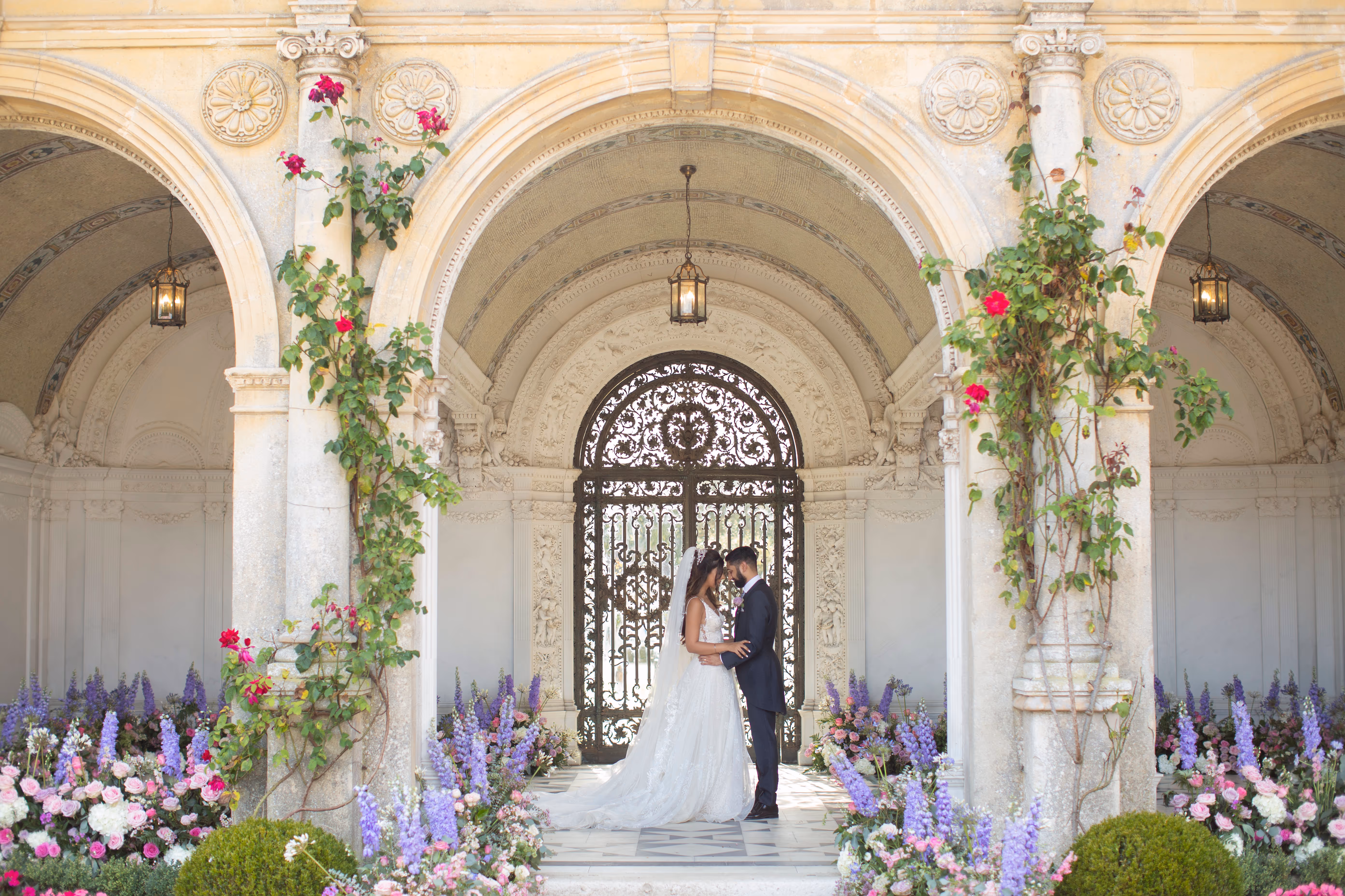 Romantic outdoor civil ceremony on a summer day at North Mymms Park's flower-filled Loggia, adorned with three marble arches