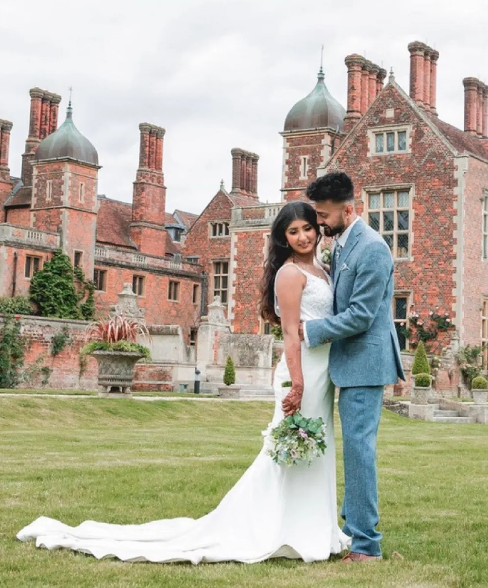Delighted bride and groom in front of the majestic Mansion House at North Mymms Park, capturing their special moment amidst its stunning grounds