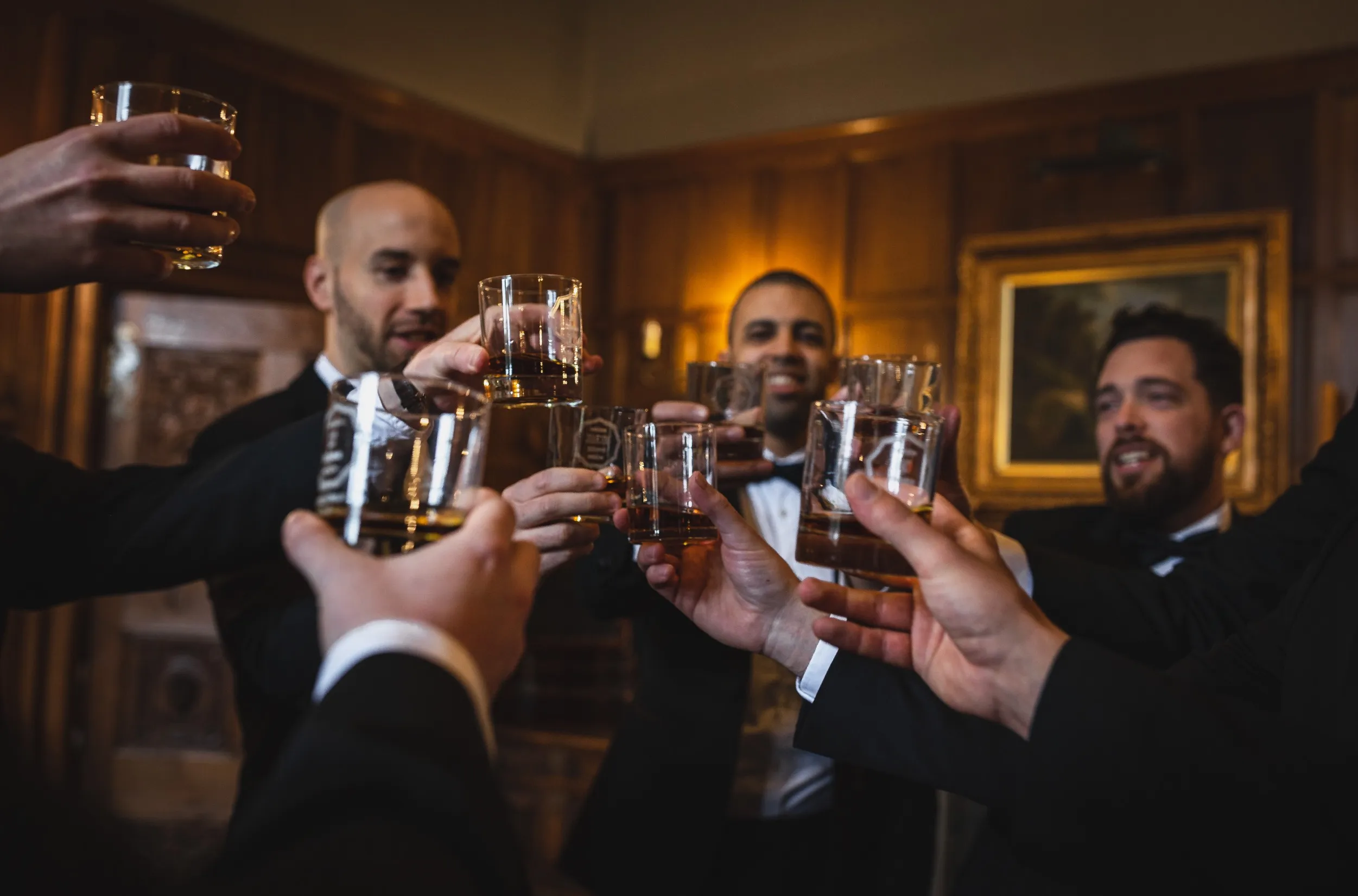 The groom and his best men raising glasses of whiskey in the oak room at North Mymms Park. Dressed in elegant black suits, they share a moment of celebration and camaraderie. The warm ambiance of the oak room, with its rich wooden decor, sets the stage for a joyous and memorable gathering. Their beaming smiles capture the happiness and excitement of the groom and his best men on this special day