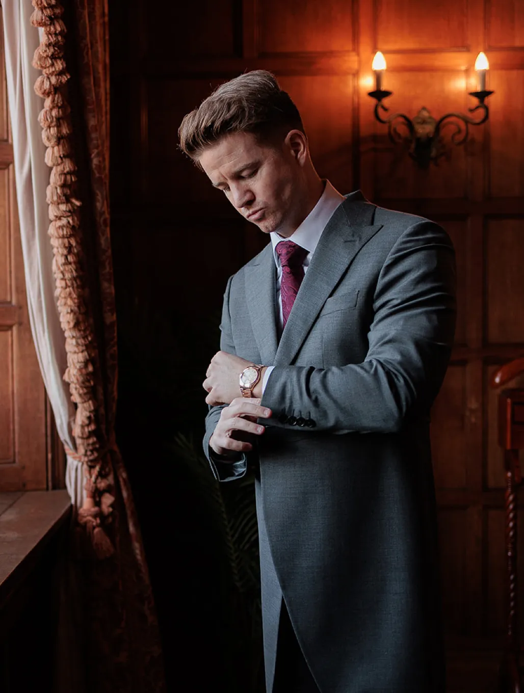 The groom is getting ready in the oak room at North Mymms Park, fixing his watch while dressed in an elegant tuxedo. The rich wooden decor of the oak room adds to the sophisticated ambiance as he prepares for his special day. The classic and timeless atmosphere captures the groom's attention to detail as he ensures everything is perfect for the upcoming wedding