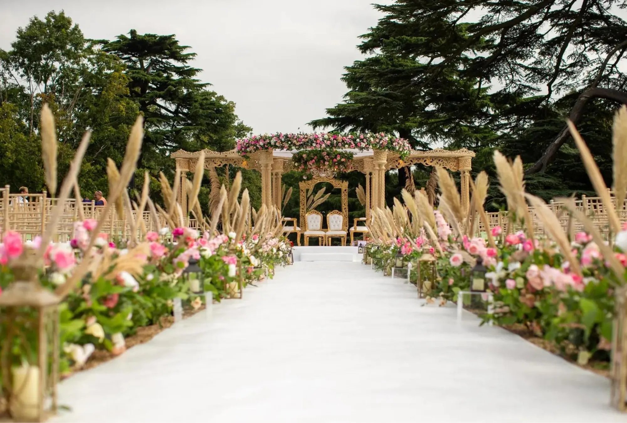 Magnificent mandap adorned with a stunning floral design, with the majestic Cedar tree standing tall in the background, creating a perfect setting for a summer wedding