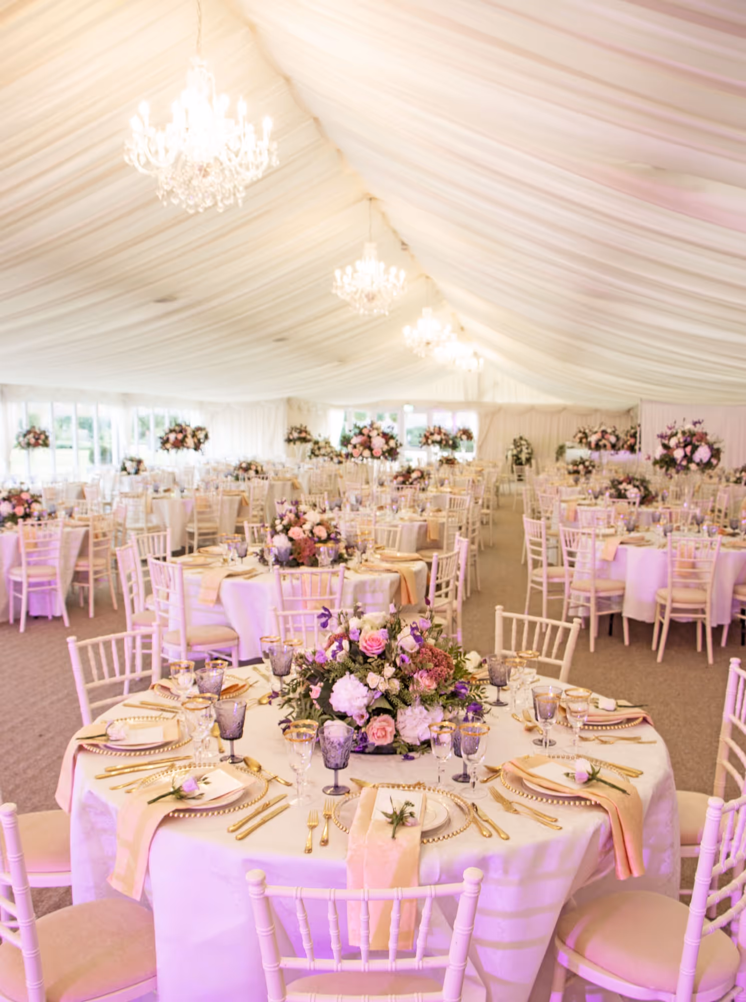 Chic, contemporary wedding reception in a sunlit pavilion, adorned with exquisite florals and upscale cutlery and glassware at North Mymms Park