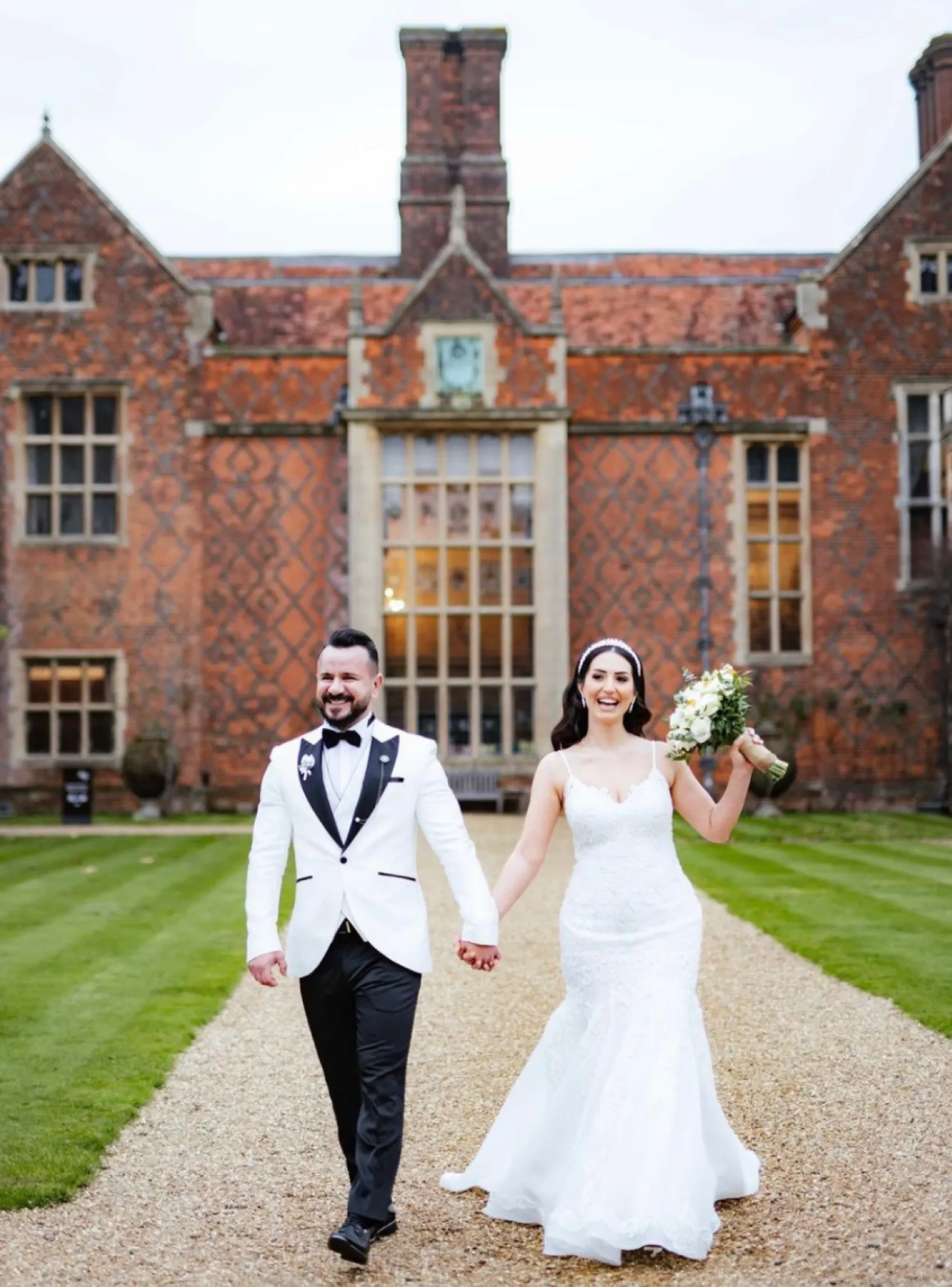 Hand in hand, the beaming bride and groom walk with smiles, the majestic Mansion House serving as a breathtaking backdrop to their special moment