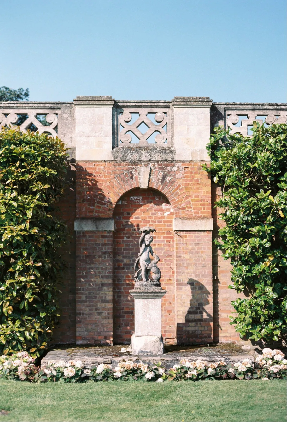 A stunning romantic garden with statues and pink roses, perfect for summer weddings