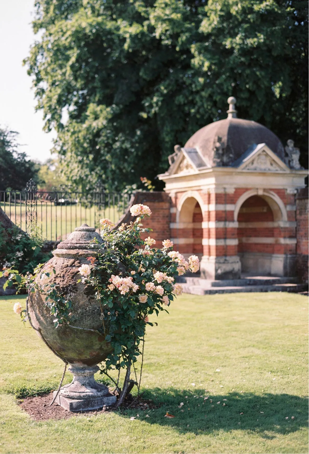 A stunning manicured garden with statues and pink roses, perfect for summer events