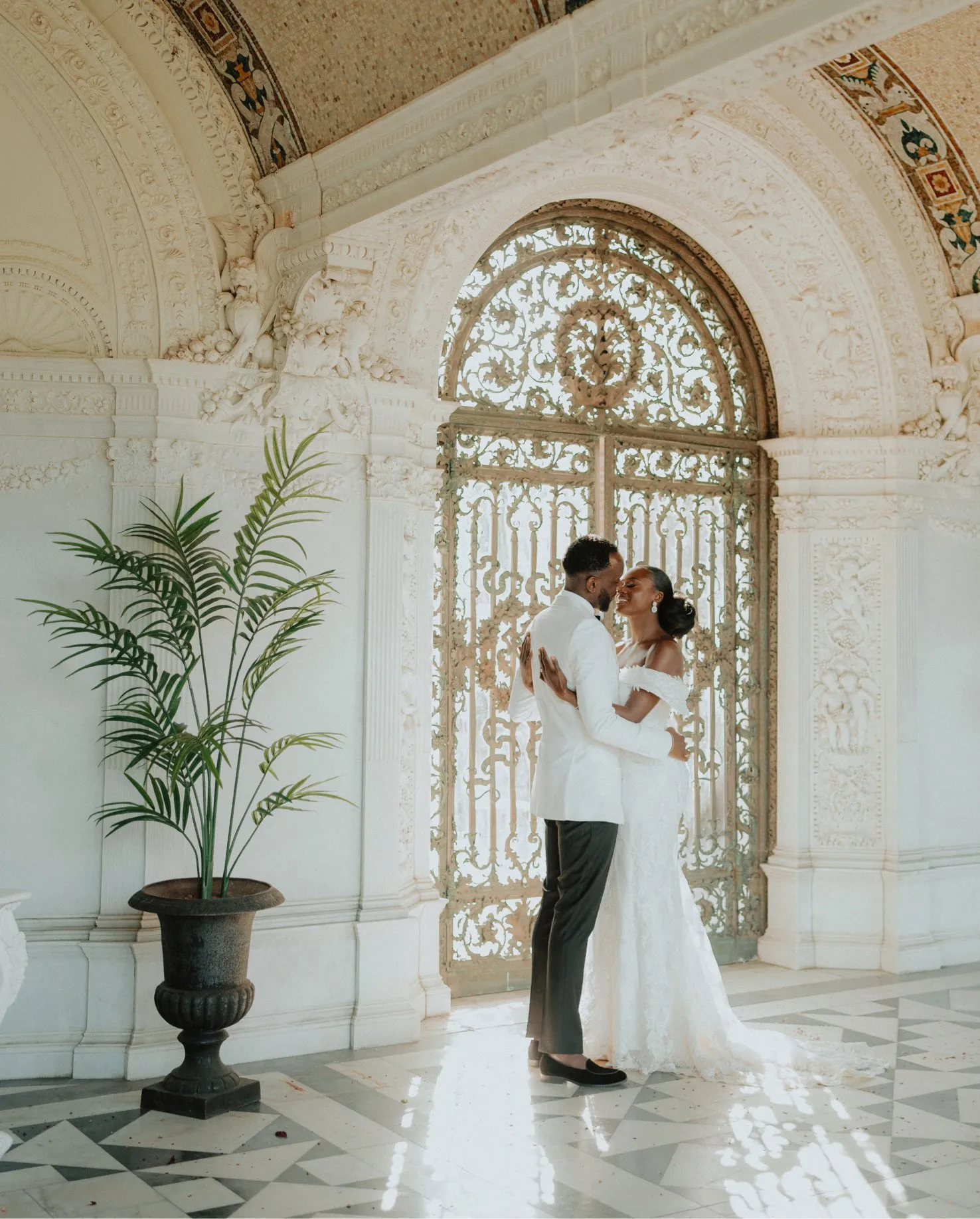 A lovely African couple holding each other, gazing affectionately into each other's eyes, inside the masterpiece Loggia at North Mymms Park. The Loggia's exquisite architecture serves as a breathtaking backdrop for this romantic moment. The couple's connection is evident as they share an intimate and tender embrace, creating a captivating and heartwarming scene in this beautiful setting