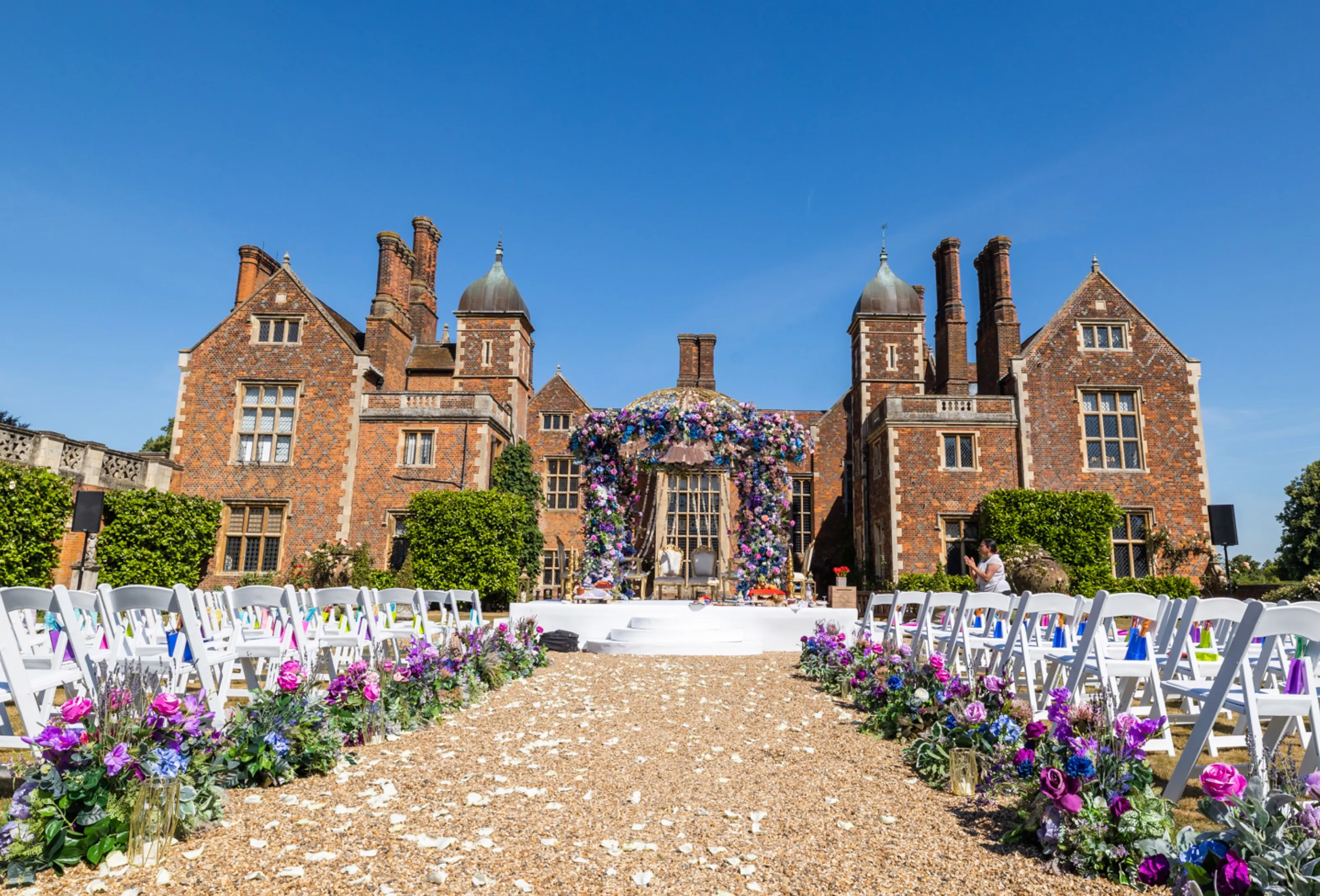 At North Mymms Park, a stunning mandap setup with an abundance of purple and pink flowers sets the stage for a beautiful religious ceremony. The breathtaking mansion house stands tall in the background, providing a picturesque setting for this special celebration. The vibrant blooms of the mandap and the majestic presence of the historic North Mymms Park create an enchanting and romantic atmosphere, making it a truly memorable wedding day