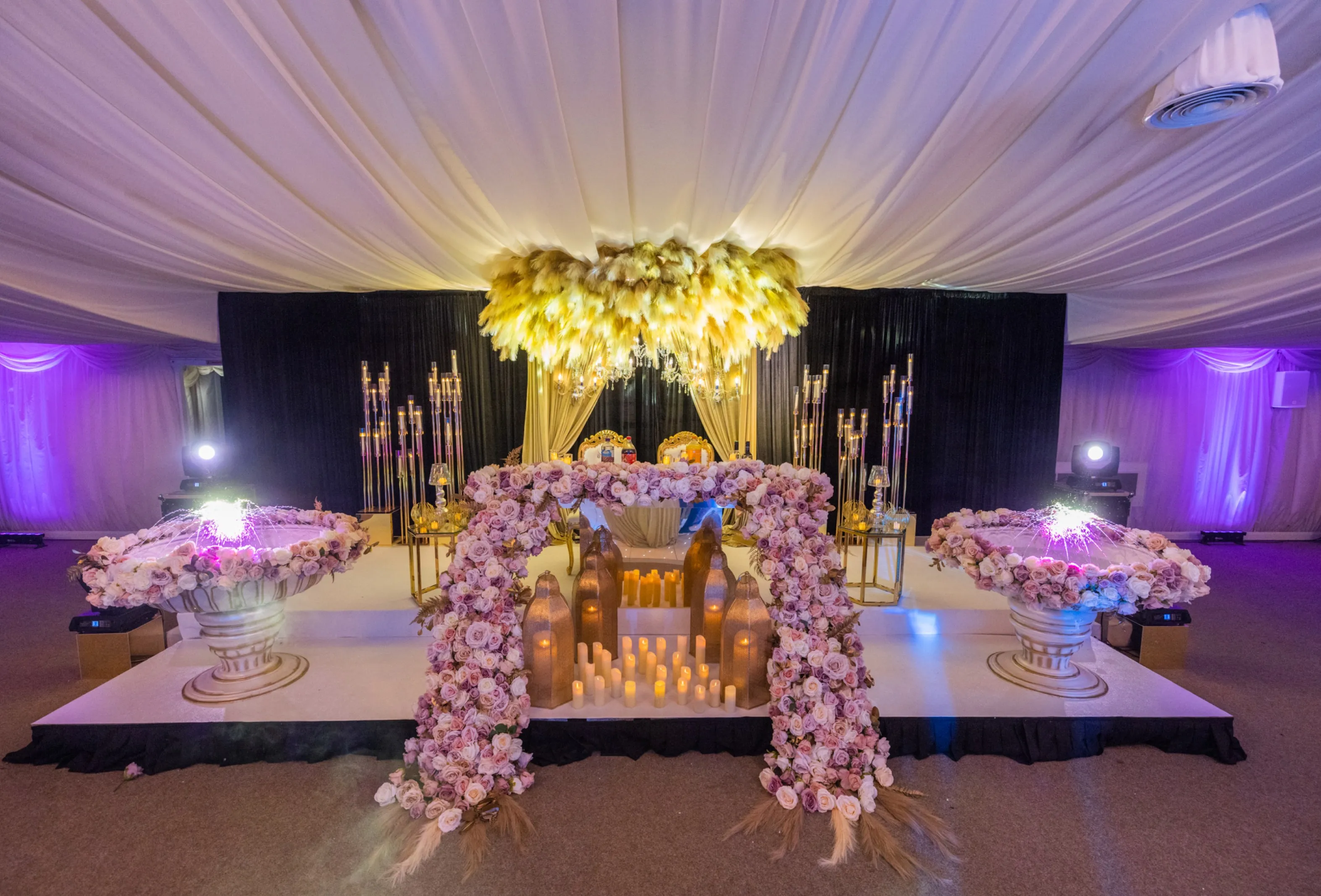 Luxurious headtable design with a chic dark wedding cake and elegant flowers, complemented by glowing candles at North Mymms Park's Pavilion
