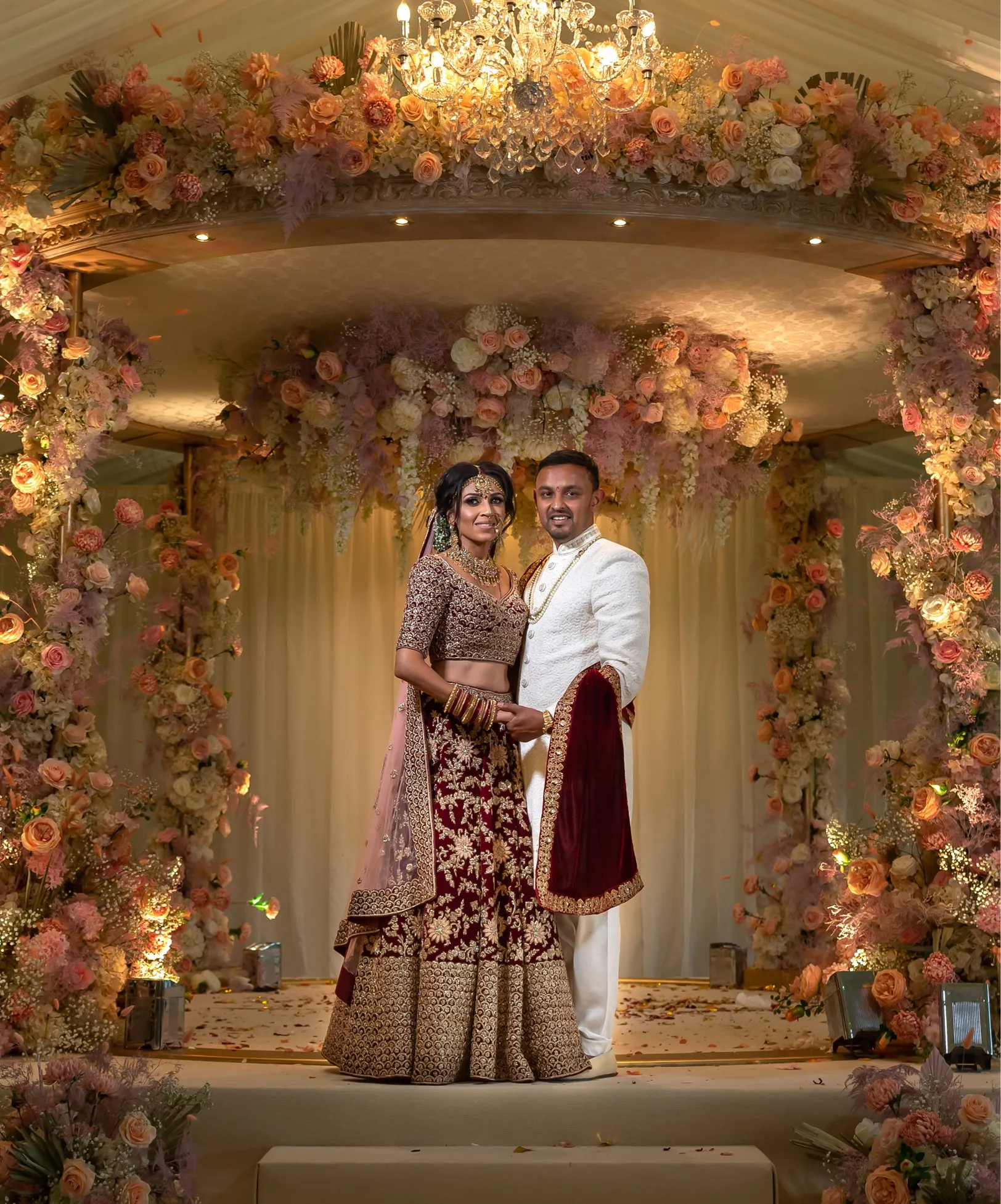 Exquisite mandap adorned with vibrant floral arrangements, featuring a joyful Asian couple during their religious ceremony in the stunning Long GalleryExquisite mandap adorned with vibrant floral arrangements, featuring a joyful Asian couple during their religious ceremony in our stunning pavilion.