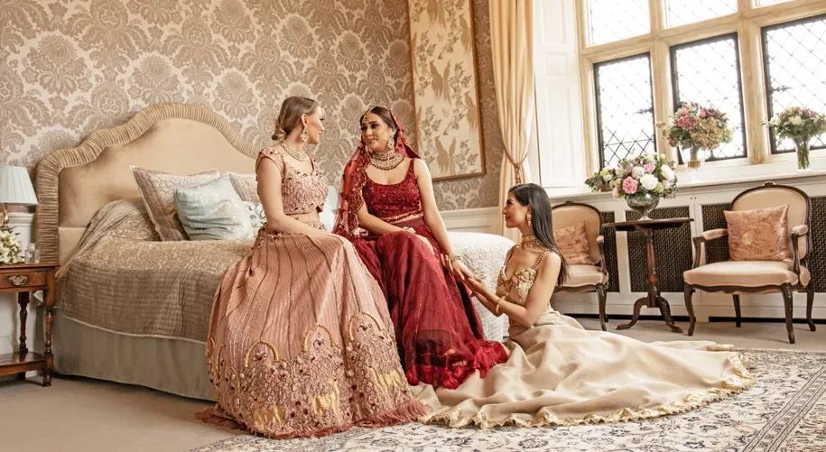 The bridesmaids seeing the bride for the first time, brimming with excitement and joy at North Mymms Park. Dressed in matching burgundy silk dresses, perfect for a Christmas wedding, their smiles light up the room. The luxurious setting of the bridal suite enhances the festive atmosphere, creating a heartwarming and memorable moment as they share in the bride's happiness on this special day