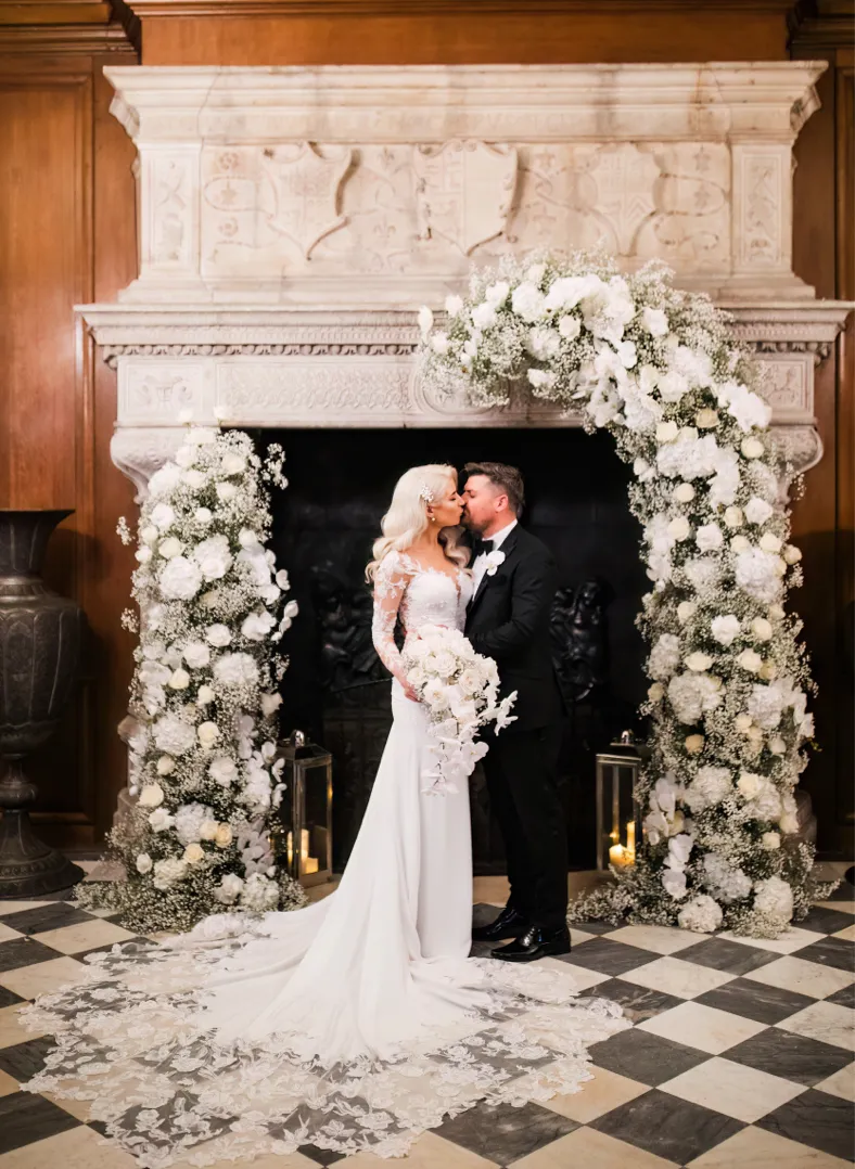 Bride and groom kissing in front of a historical fire place in the Marble Hall, North mymms Park