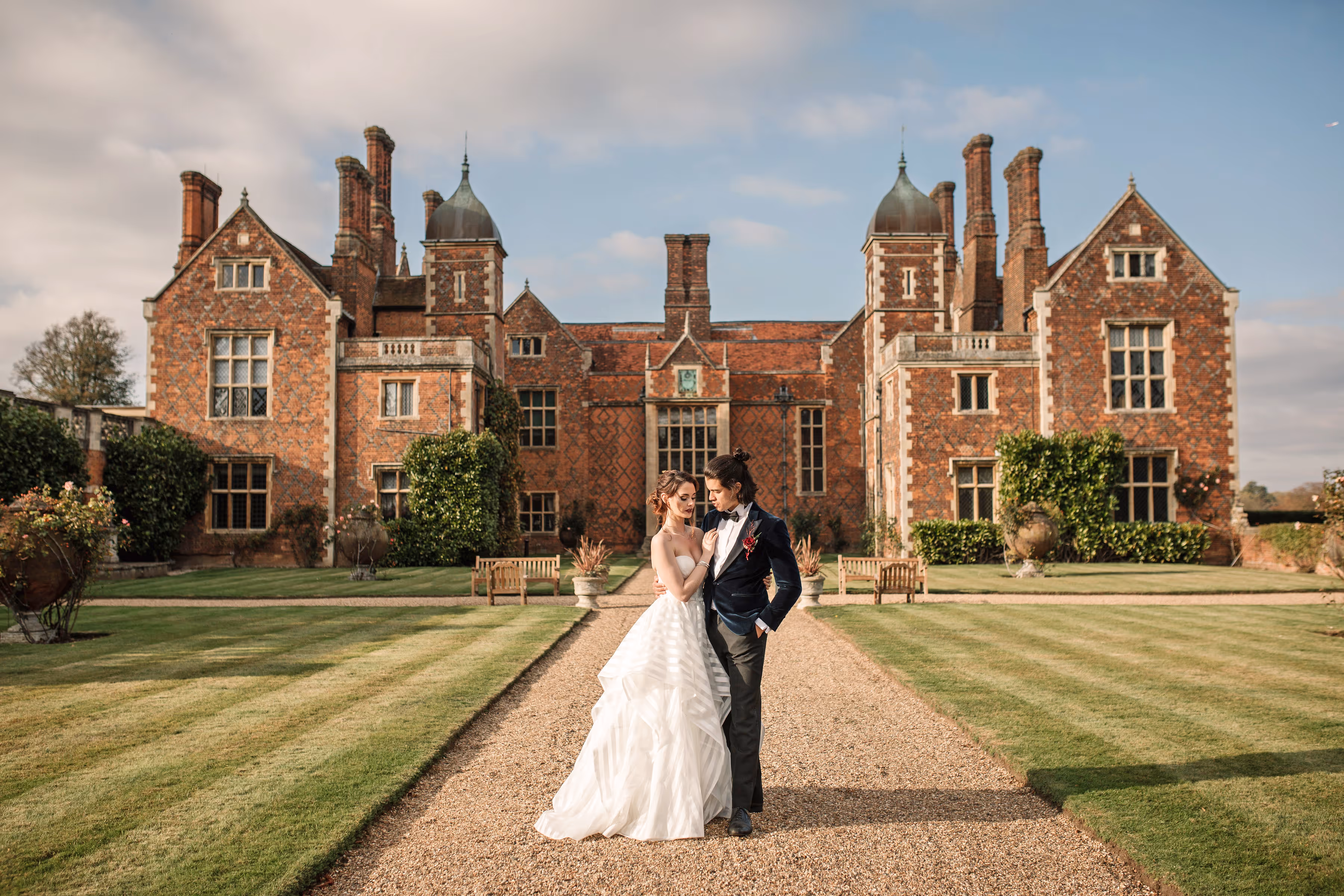 Portrait of a bride and groom standing together in front of North Mymms Park, an elegant 16th-century Elizabethan mansion surrounded by 400 acres of scenic grounds, showcasing the venue's beauty as an ideal wedding location in Hertfordshire