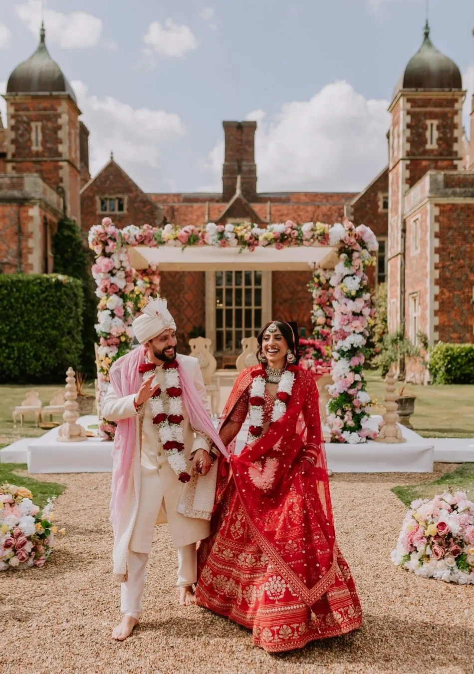 A picture-perfect moment captured at North Mymms Park. The newlyweds stand on a historic and elegant wooden staircase, gazing into each other's eyes. The staircase is adorned with an abundance of white flowers, adding a touch of timeless beauty to the scene. The combination of the historic setting and the delicate floral decorations creates a romantic and unforgettable moment for the happy couple on their special day