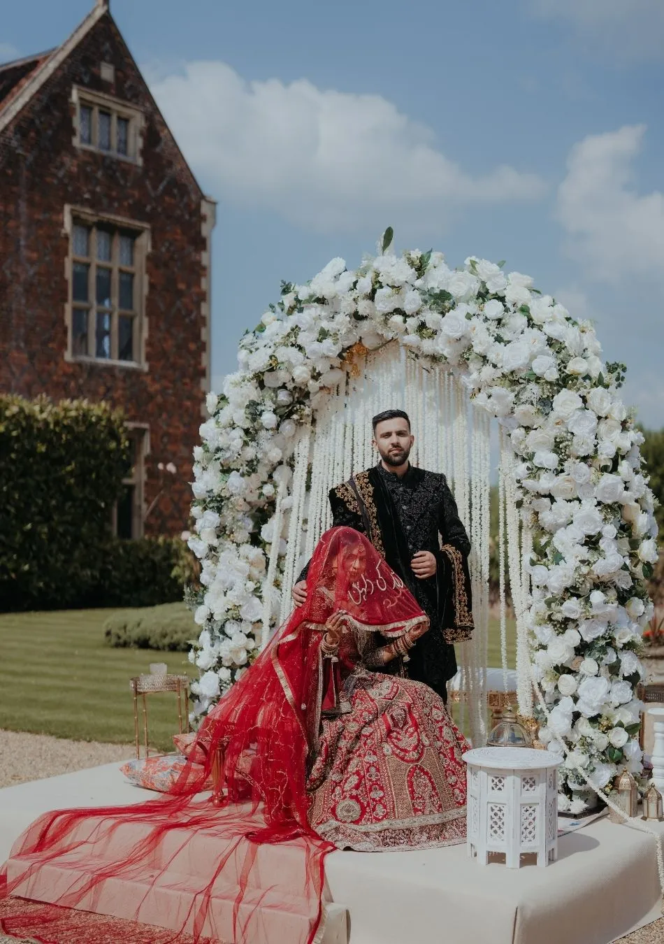 Lovely English bride standing in North Mymms Park's Marble Hall, in front. of a historical fireplace adorned with white roses