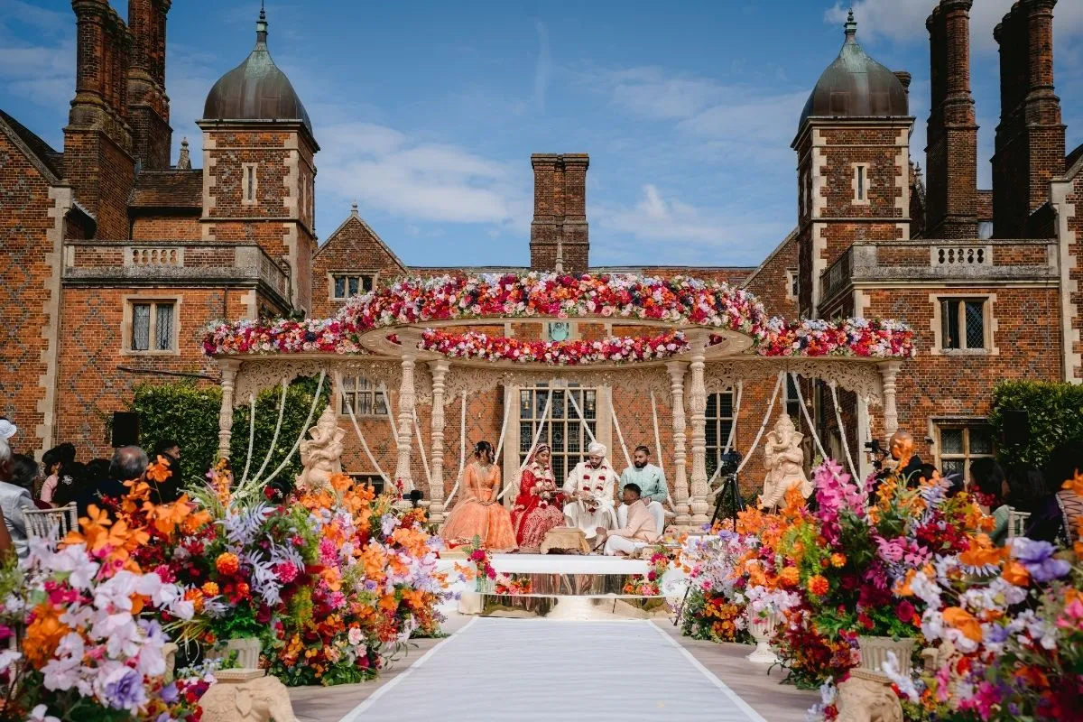 A colorful and stunning, heatbale design with an array of vibrant flowers, flickering candles, and purple lighting inside the modern pavilion at North Mymms Park. The captivating decor adds a sense of enchantment to the space, creating a perfect ambiance for a joyous and celebratory event. The modern pavilion's sleek design complements the lively and vibrant atmosphere, making it an unforgettable and magical setting for any special occasion