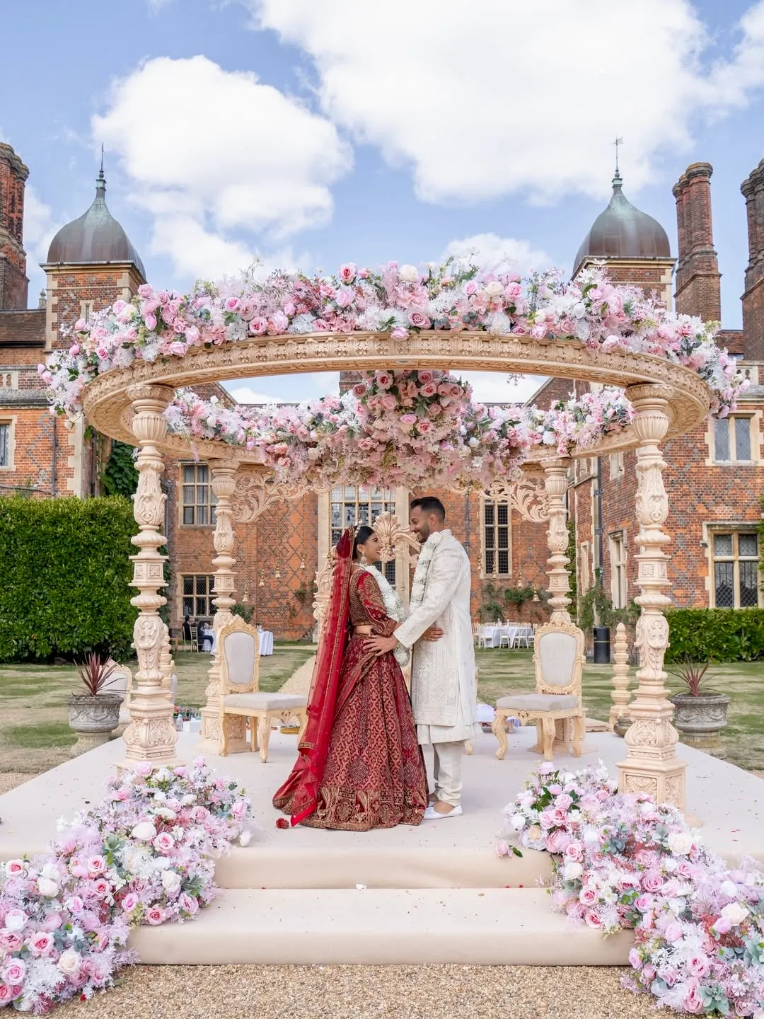 Exquisite mandap adorned with vibrant floral arrangements, featuring a joyful Asian couple during their religious ceremony in the stunning Long GalleryExquisite mandap adorned with vibrant floral arrangements, featuring a joyful Asian couple during their religious ceremony in our stunning pavilion.
