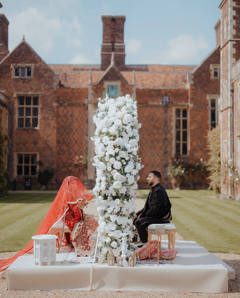 Exquisite mandap adorned with vibrant floral arrangements, featuring a joyful Asian couple during their religious ceremony in the stunning Long GalleryExquisite mandap adorned with vibrant floral arrangements, featuring a joyful Asian couple during their religious ceremony in our stunning pavilion.