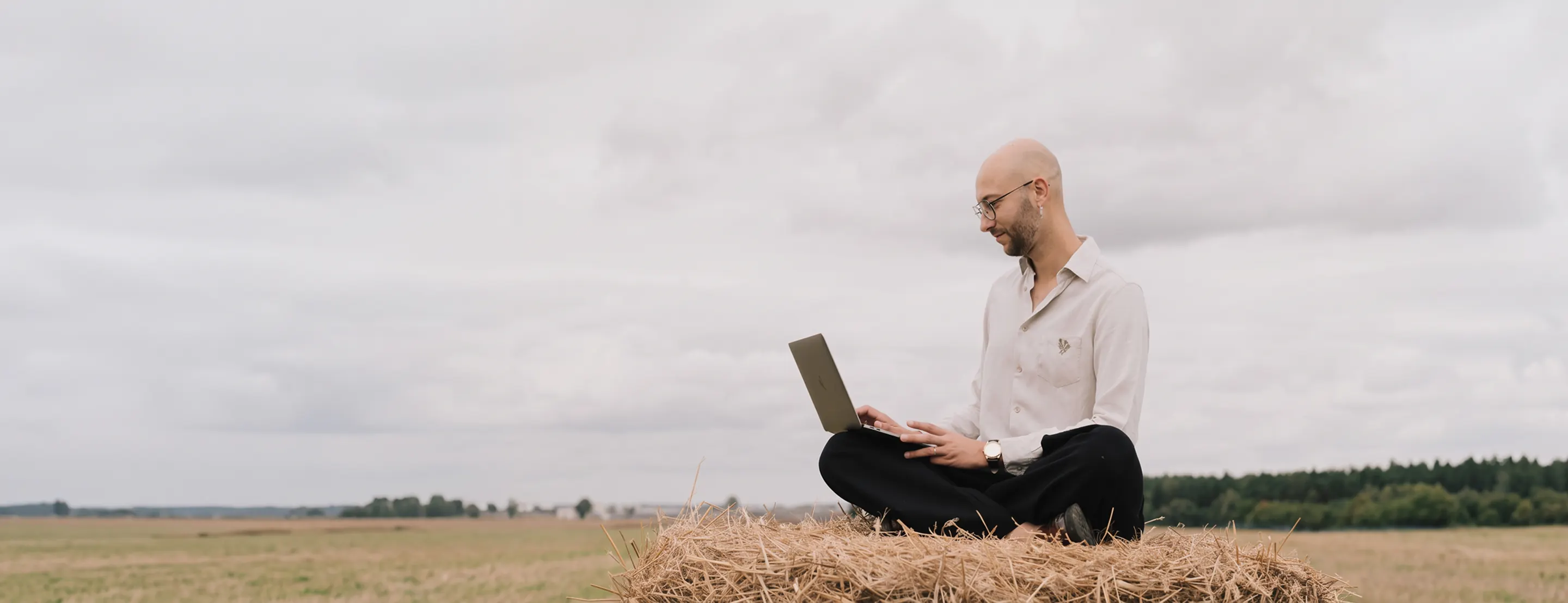 Kacper Kij, merkevaredesigner i Haugesund, med laptop på et jorde