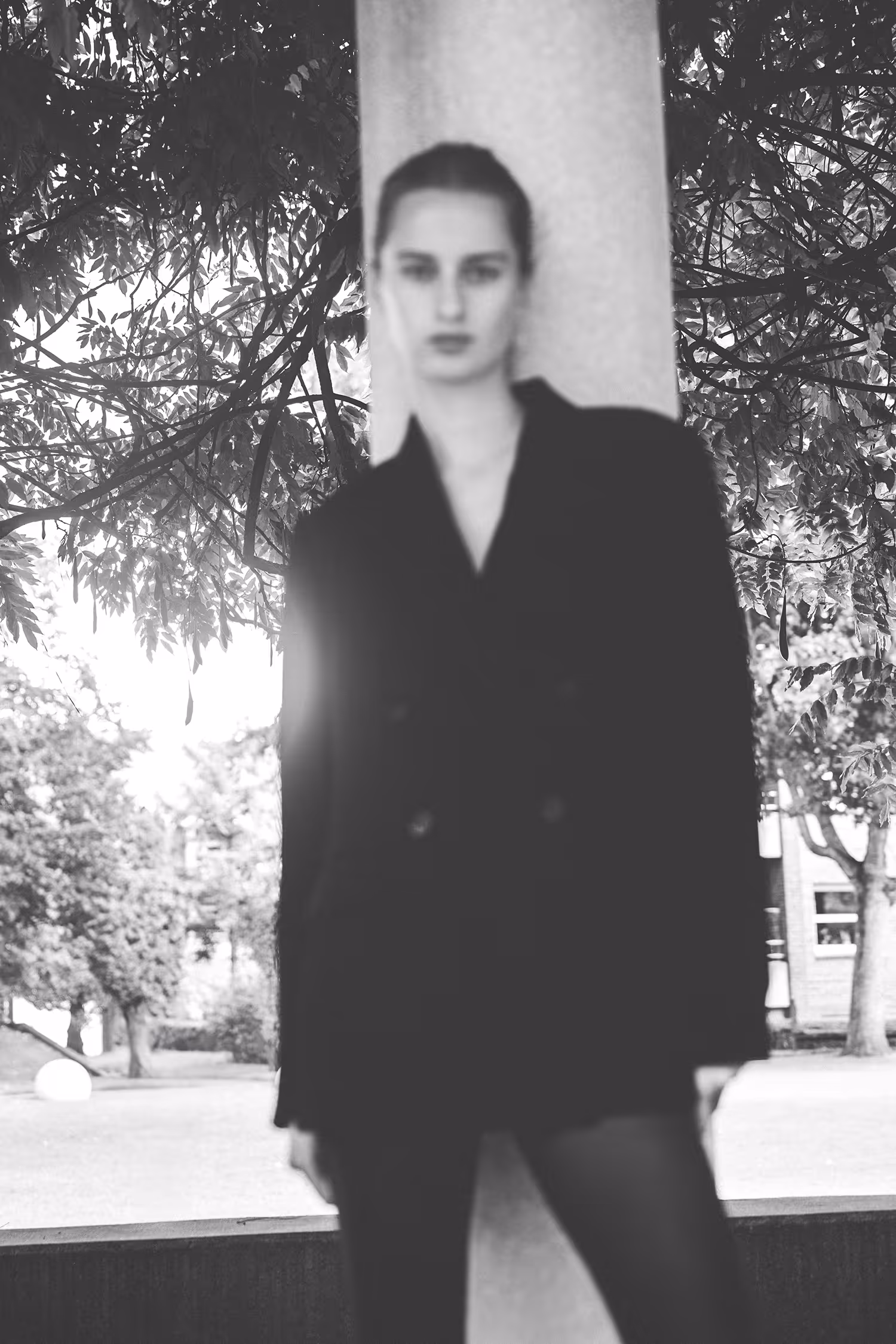 A woman in a black blazer standing by a column