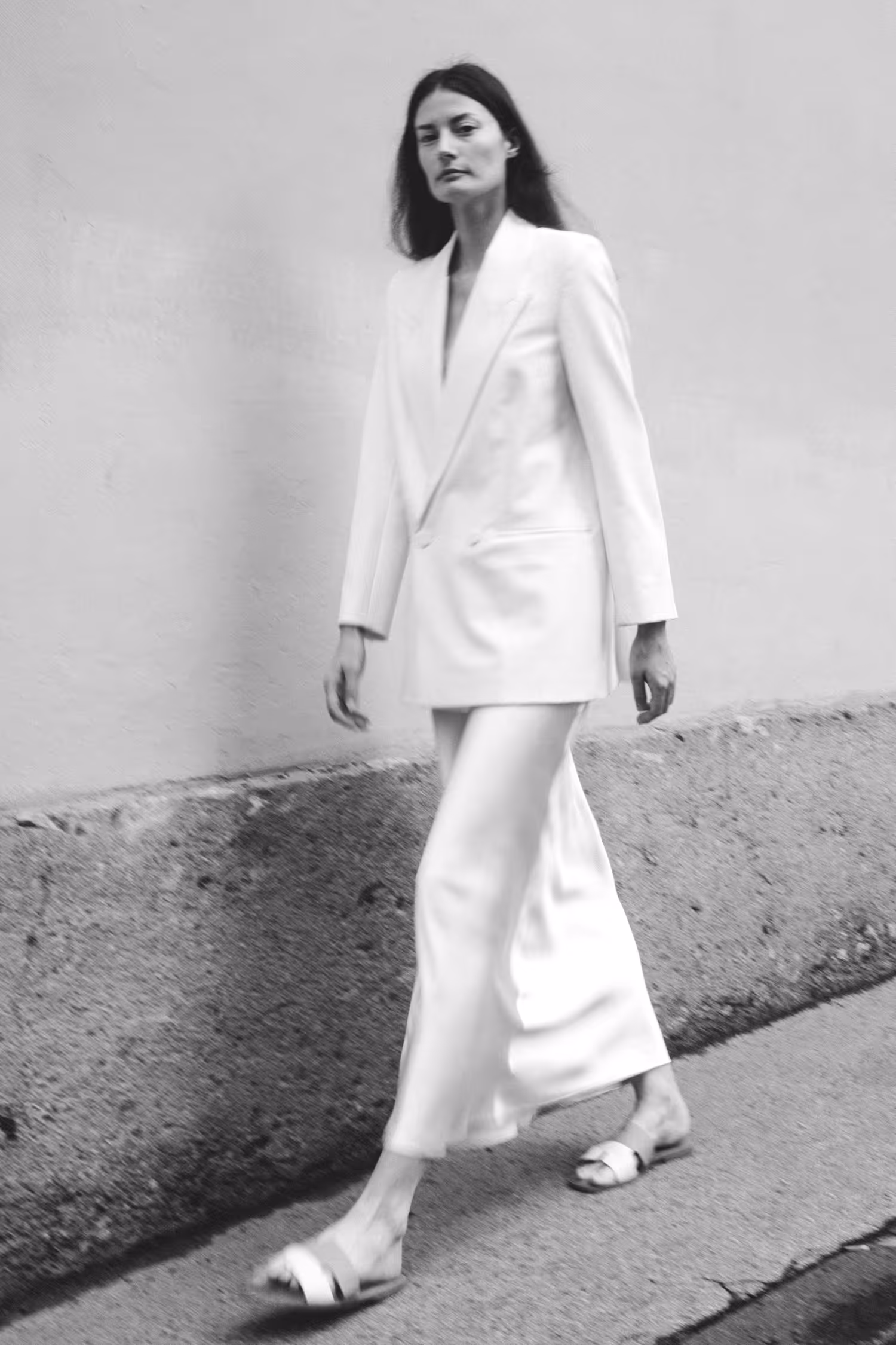 A woman dressed in white walking by the wall