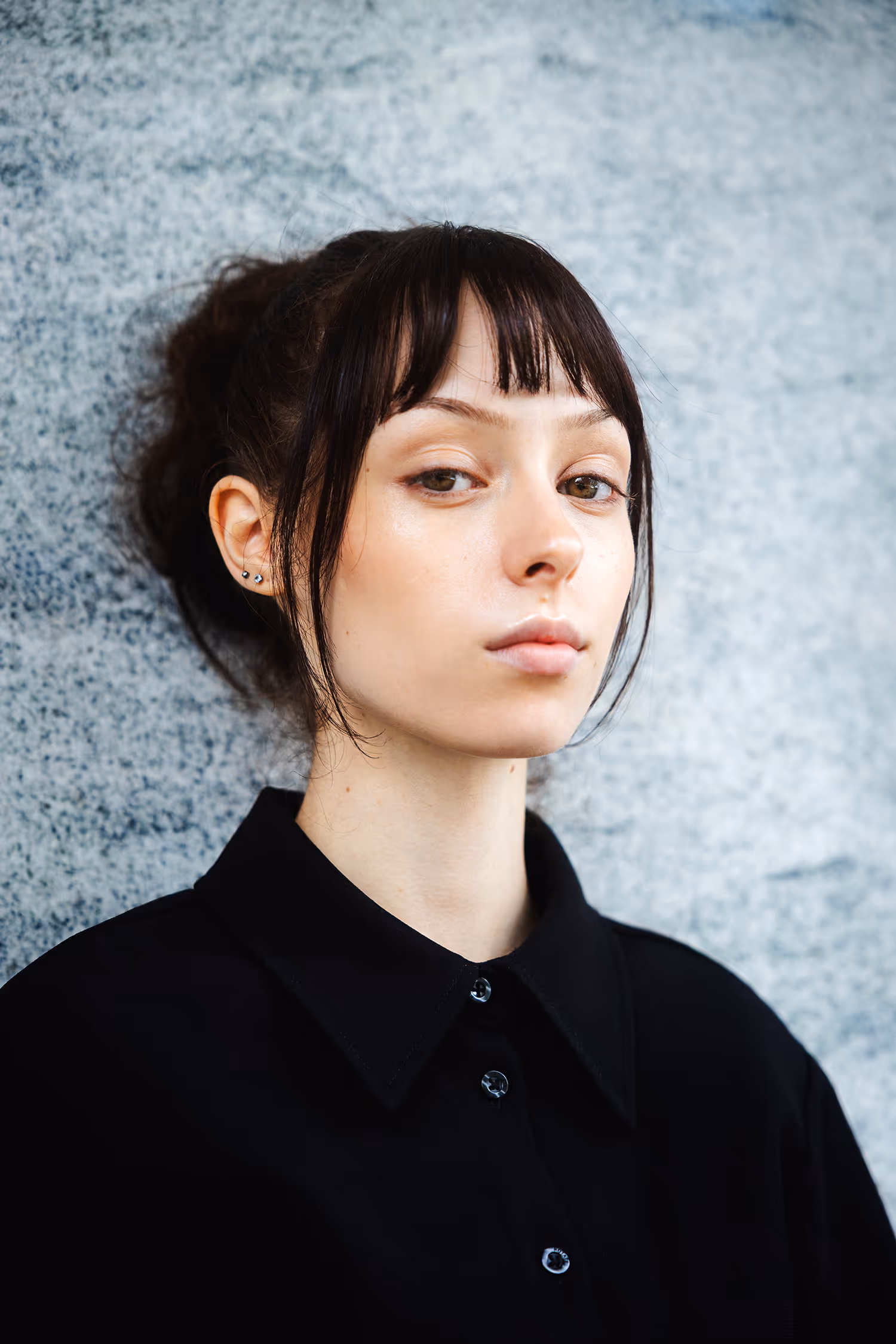 A woman dressed in black standing by the wall