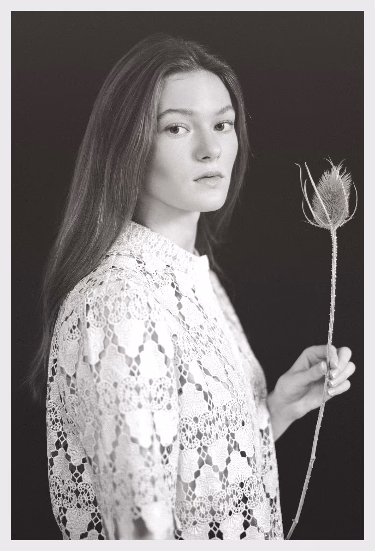 A woman in an embroidered blouse holding a dried Cardistelli flower