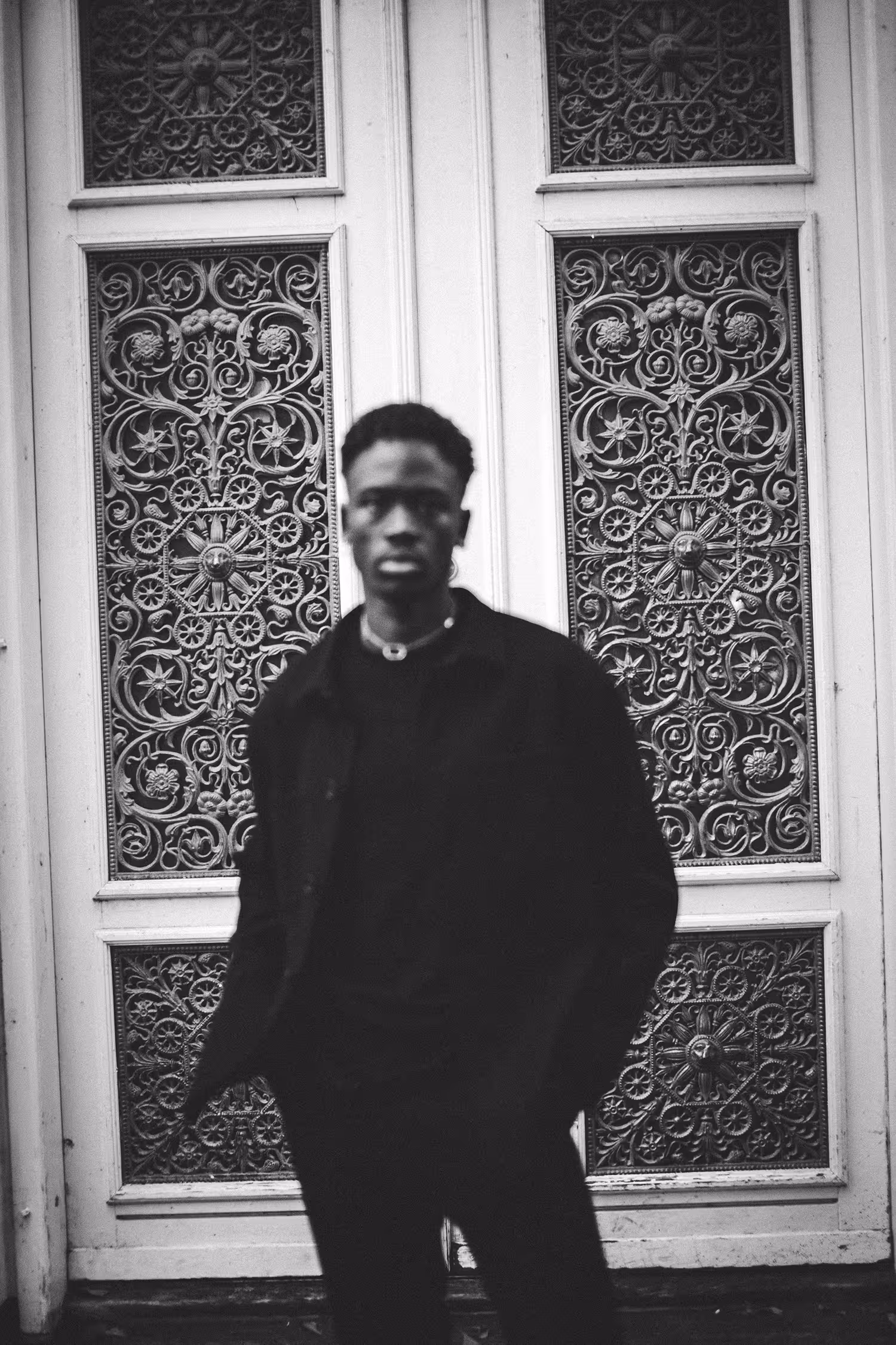 Man dressed in black standing against decorative doors