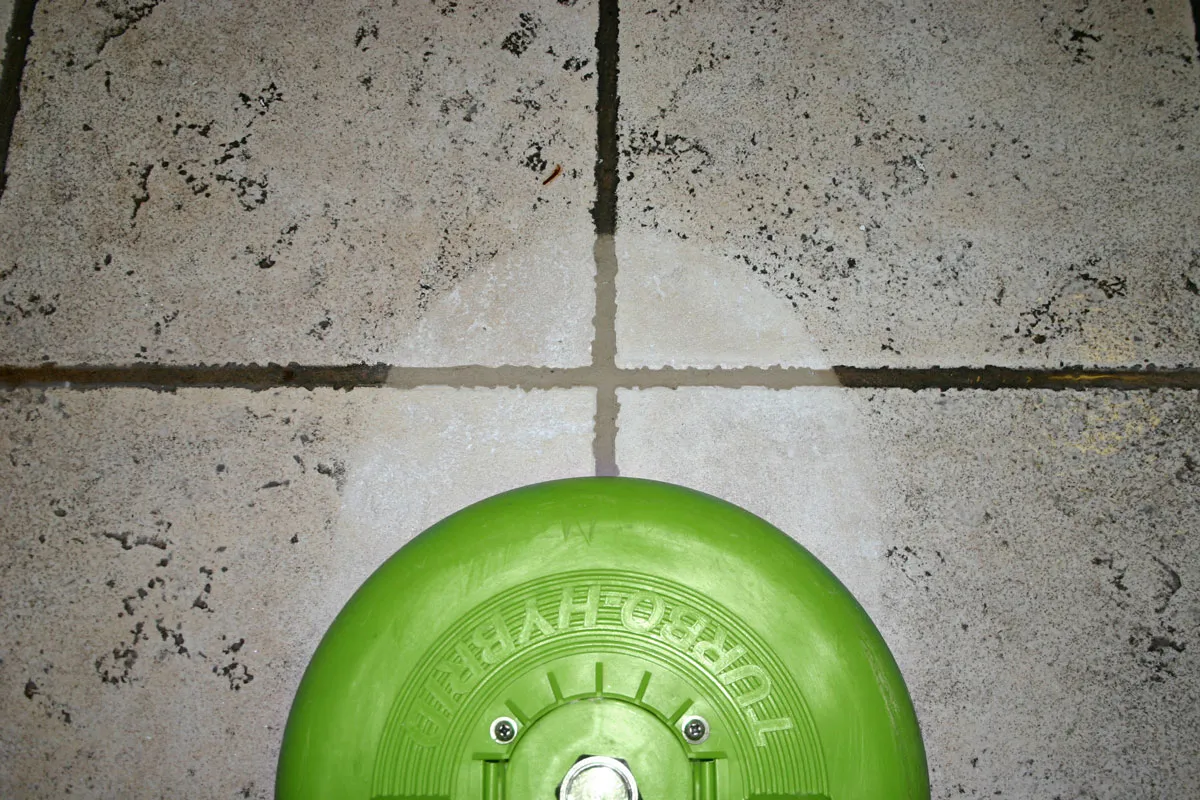 Rotary tile-cleaning tool working across tile and grout lines.