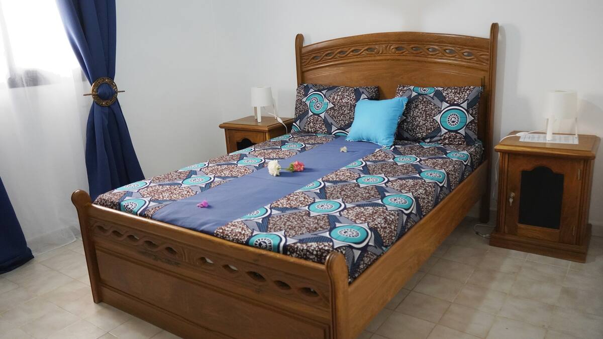 lit en bois foncé avec des draps bleus
