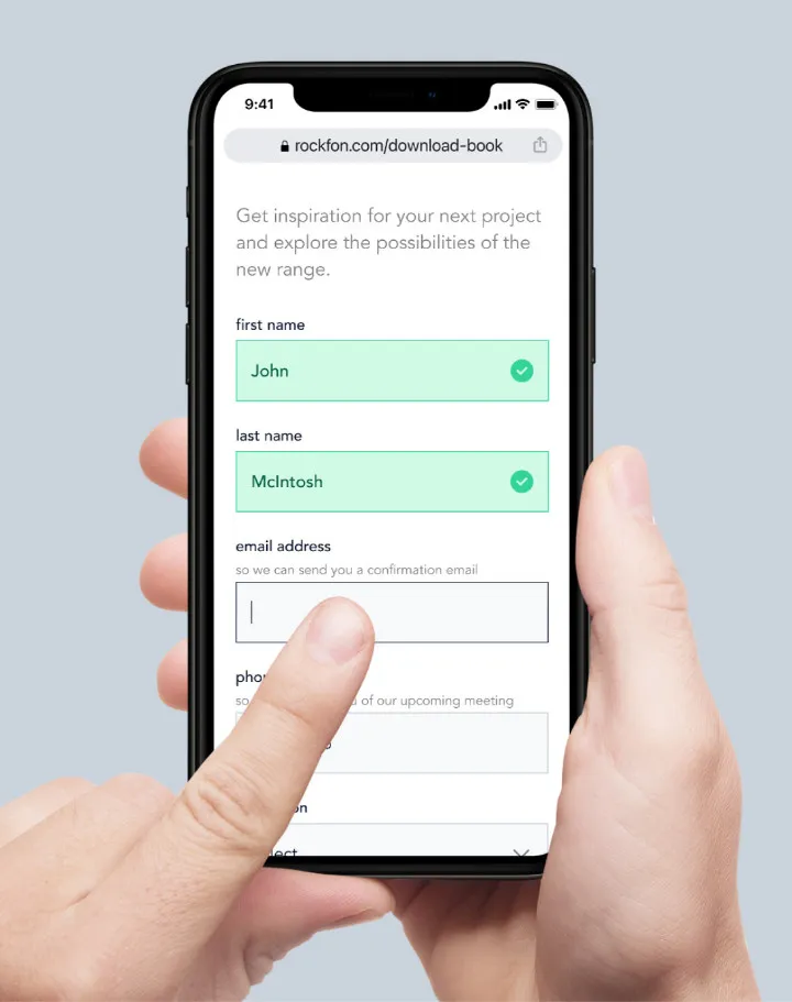 Hand holding a phone showing the new Rockfon lead capture pages, or forms.
