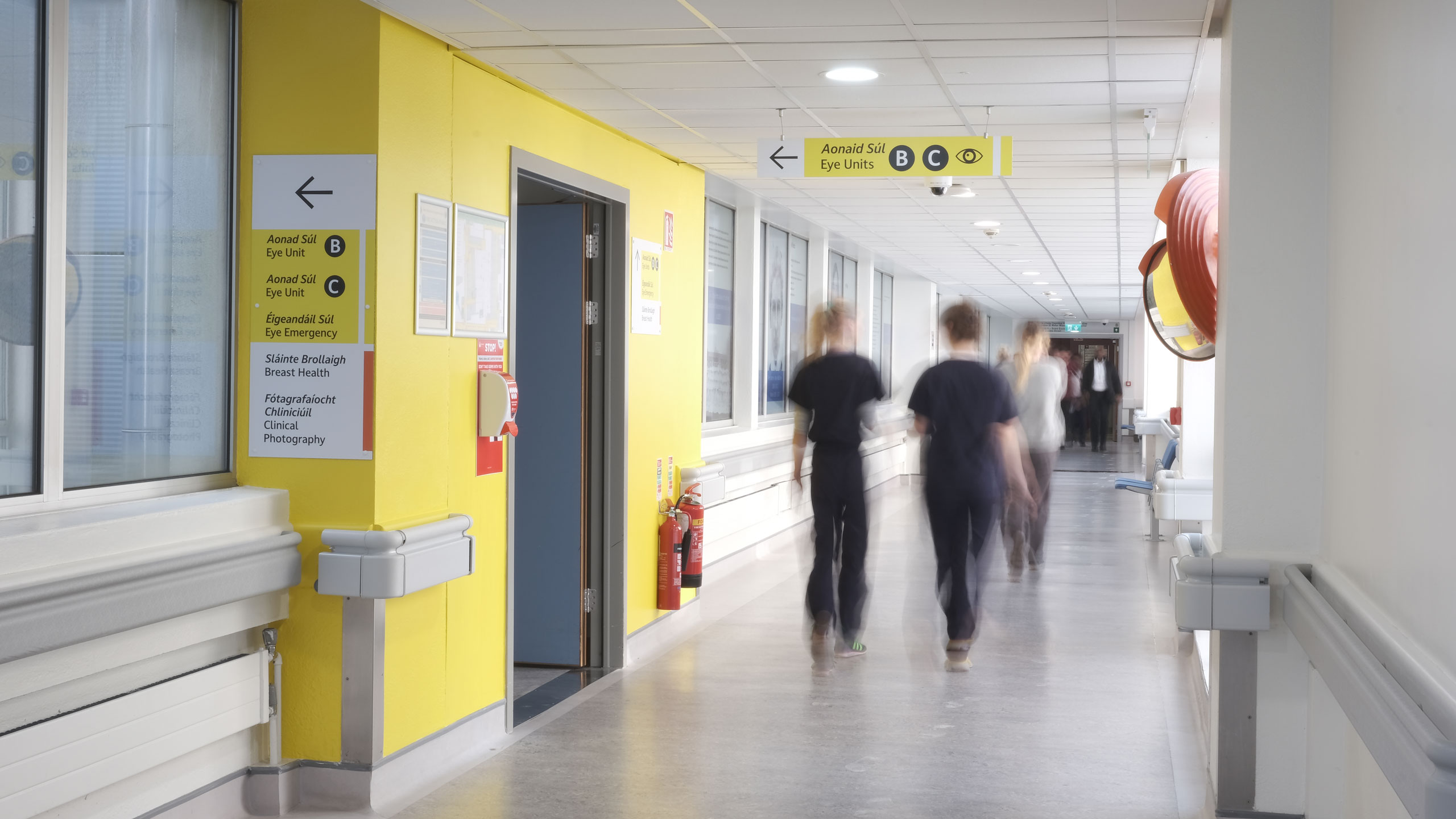 People walking pas the Eye Department Units B, C and Eye Emergency at the Mater HospitalL. The Eye Department at the Mater Hospital is denoted the yellow color. Follow the yellow signs to the Eye Department