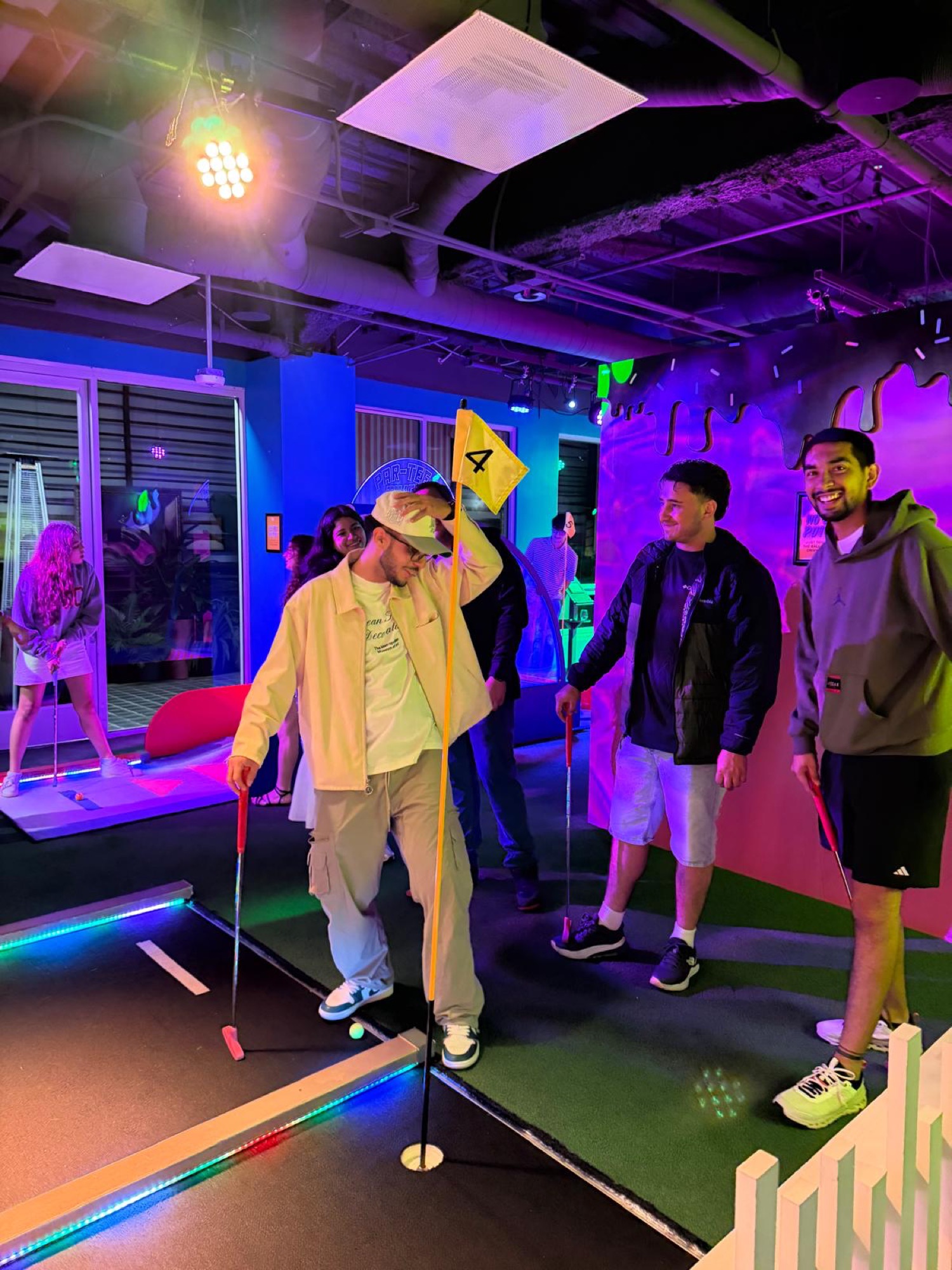 CWC students putting at a neon-lit mini golf hole during a social outing — English speaking practice extends beyond the classroom