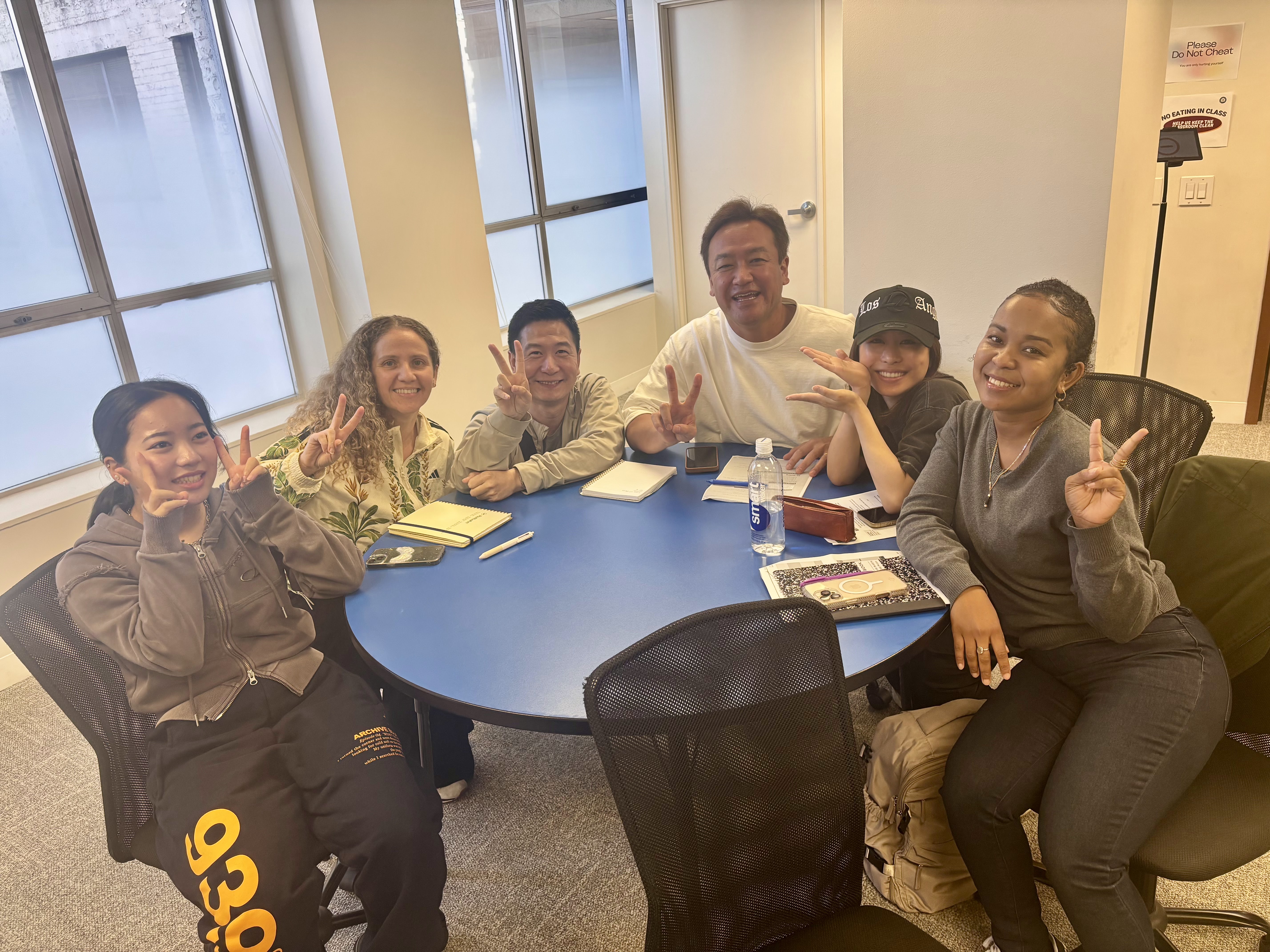 Five CWC students smiling during group study at a round table, building daily habits to learn English fast together