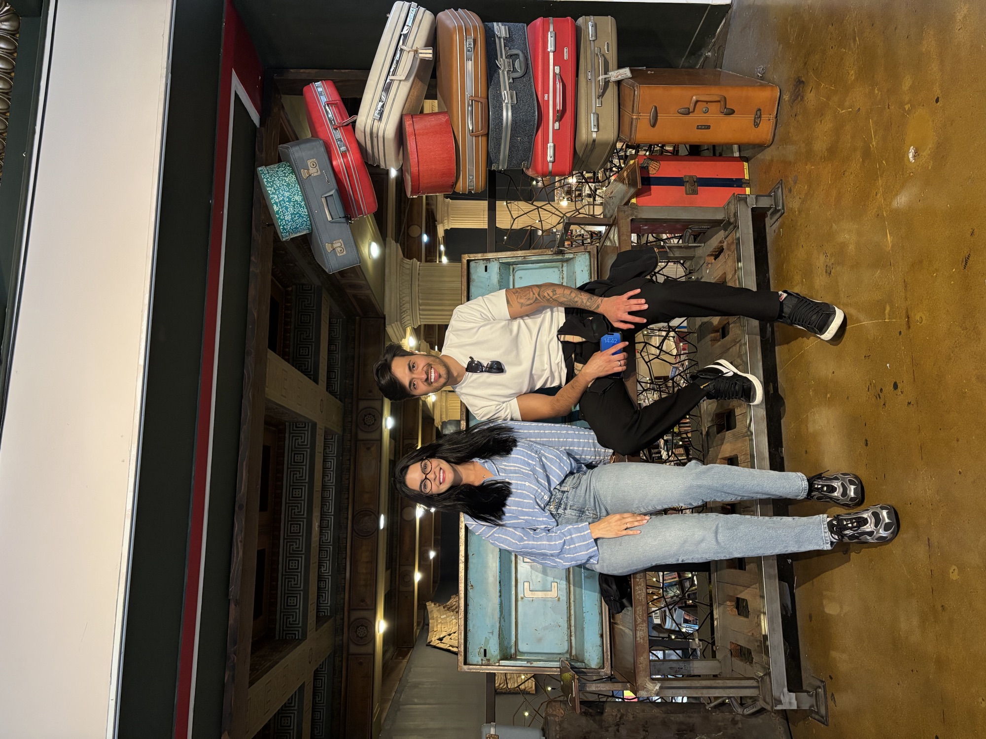 CWC students posing with vintage suitcases display at The Last Bookstore in Los Angeles, embracing the learning journey of how to learn English at Columbia West College