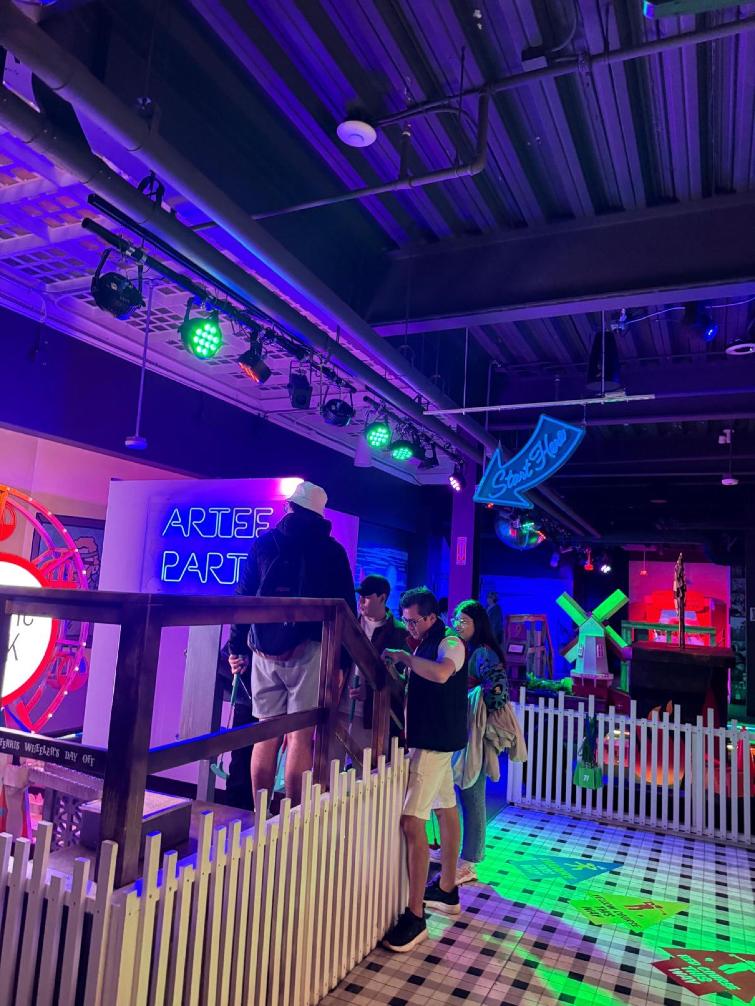 Neon-lit interior of the mini golf venue during a CWC social outing, where students practice English business communication in real-world settings