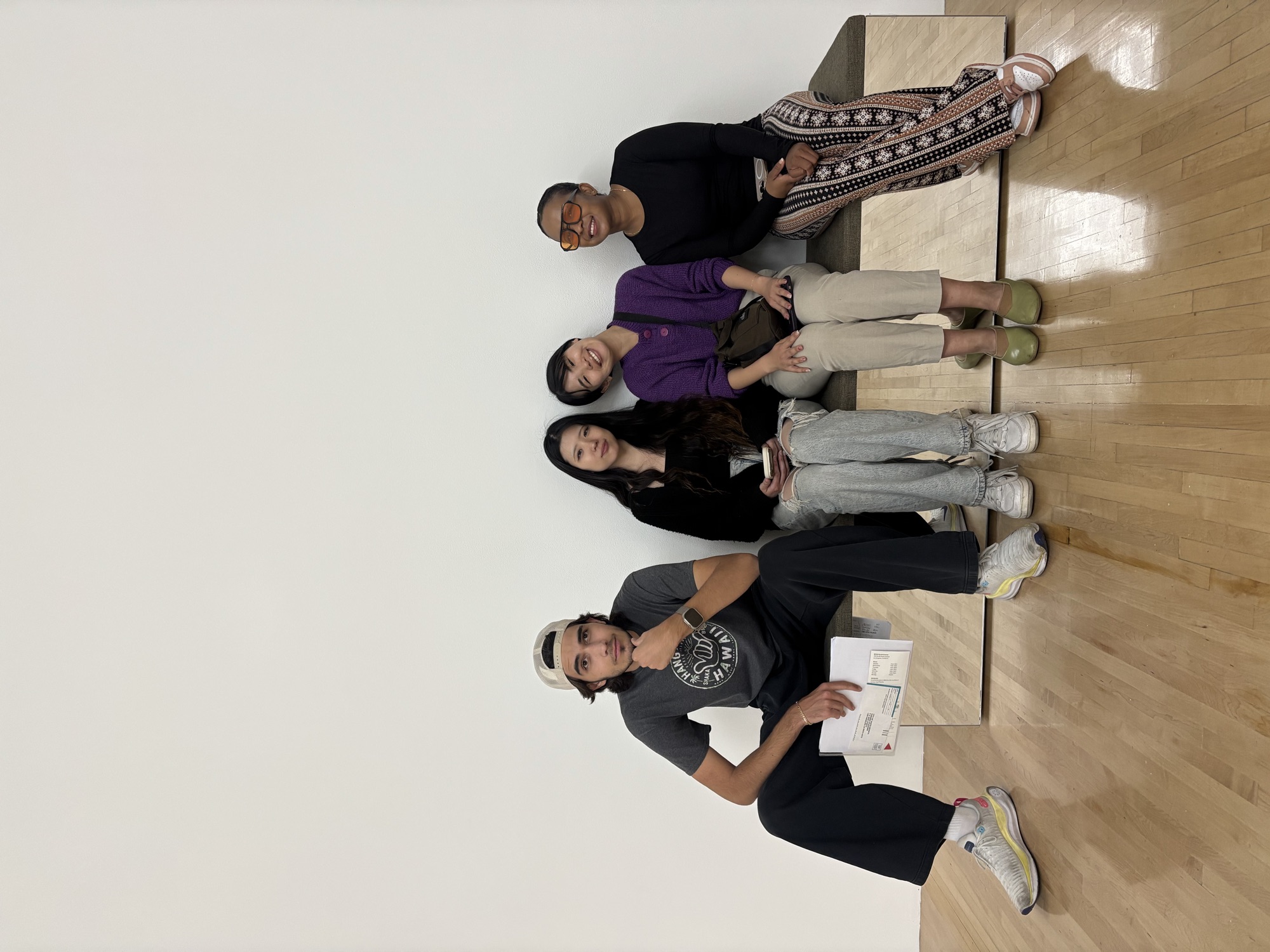 CWC students seated by a white gallery wall at MOCA, discussing how to speak English fluently during a cultural outing