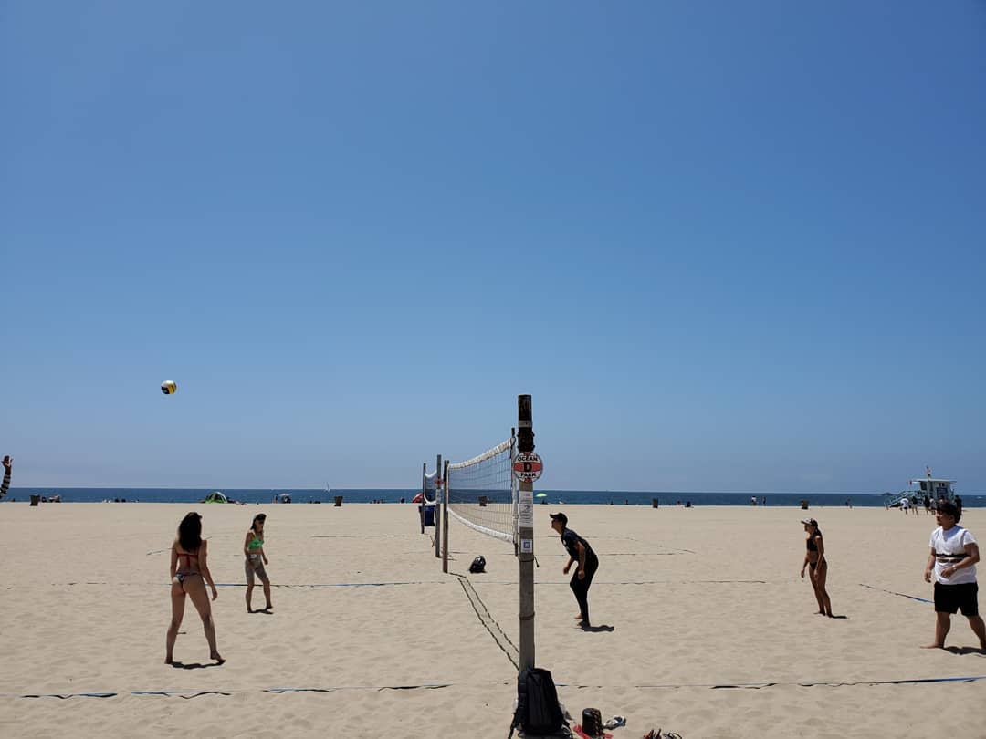 CWC students playing beach volleyball at an LA beach, enjoying English conversation practice in a relaxed outdoor setting