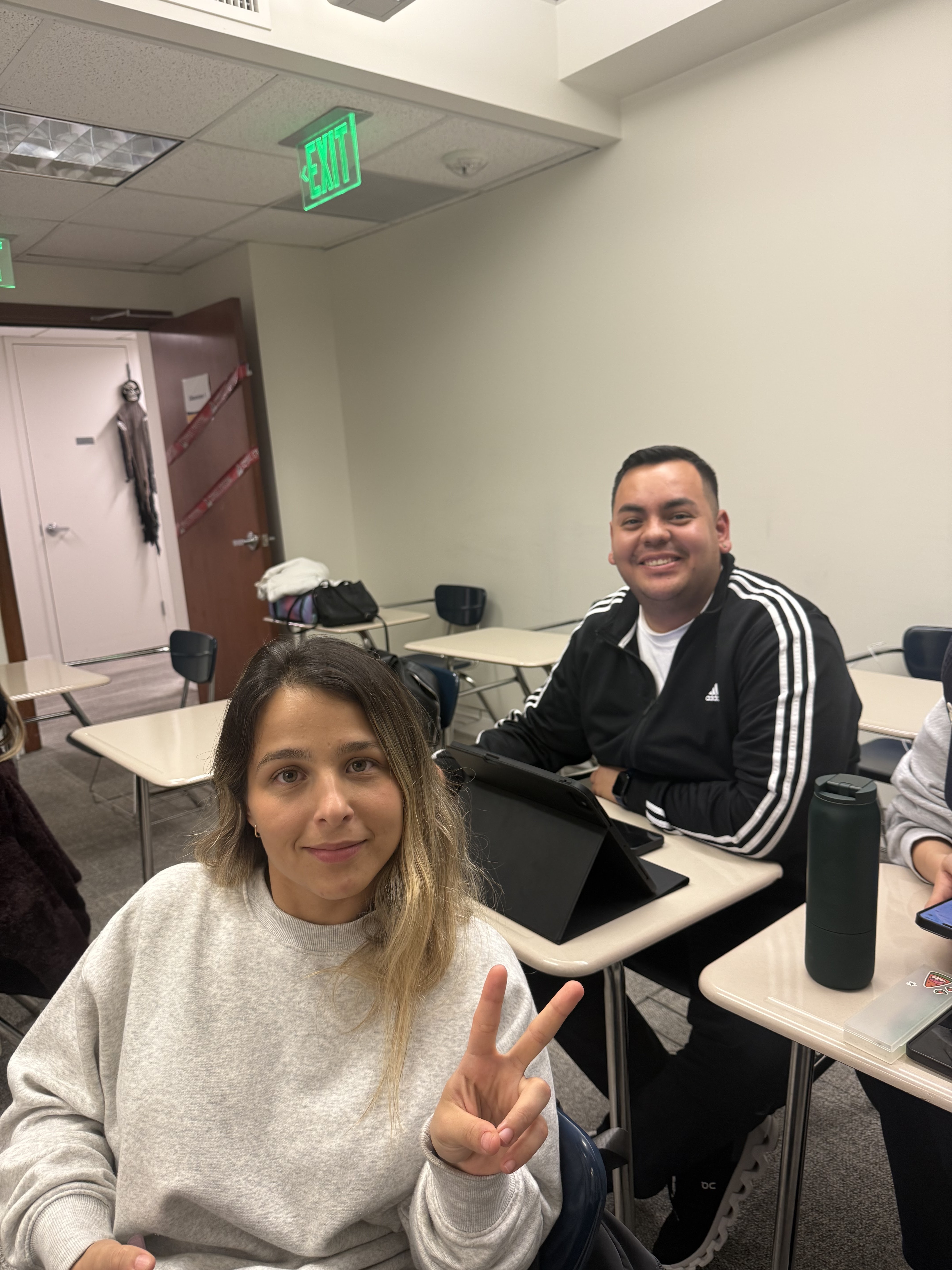 Two Columbia West College students taking a friendly classroom selfie, reflecting the supportive learning environment for English conversation beginners