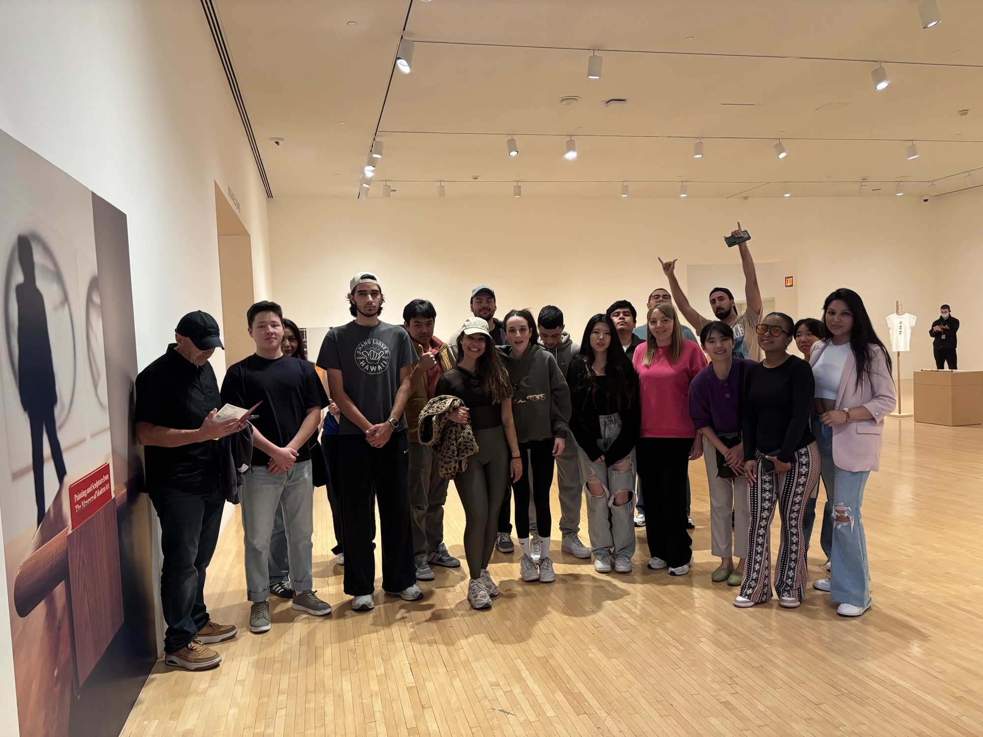 CWC student group with raised hands having fun at a MOCA exhibit — learning English slang through real cultural experiences at Columbia West College