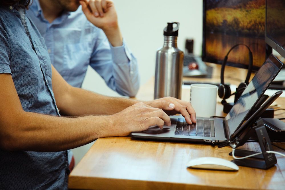 developer typing on macbook pro at desk