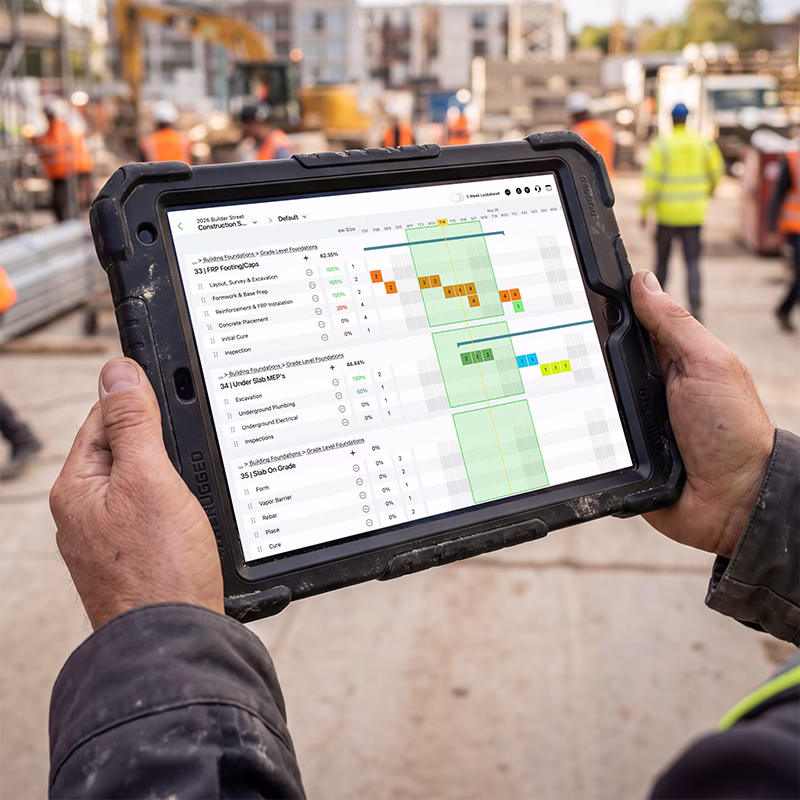 Person holding rugged tablet showing construction project schedule with tasks and progress percentages.