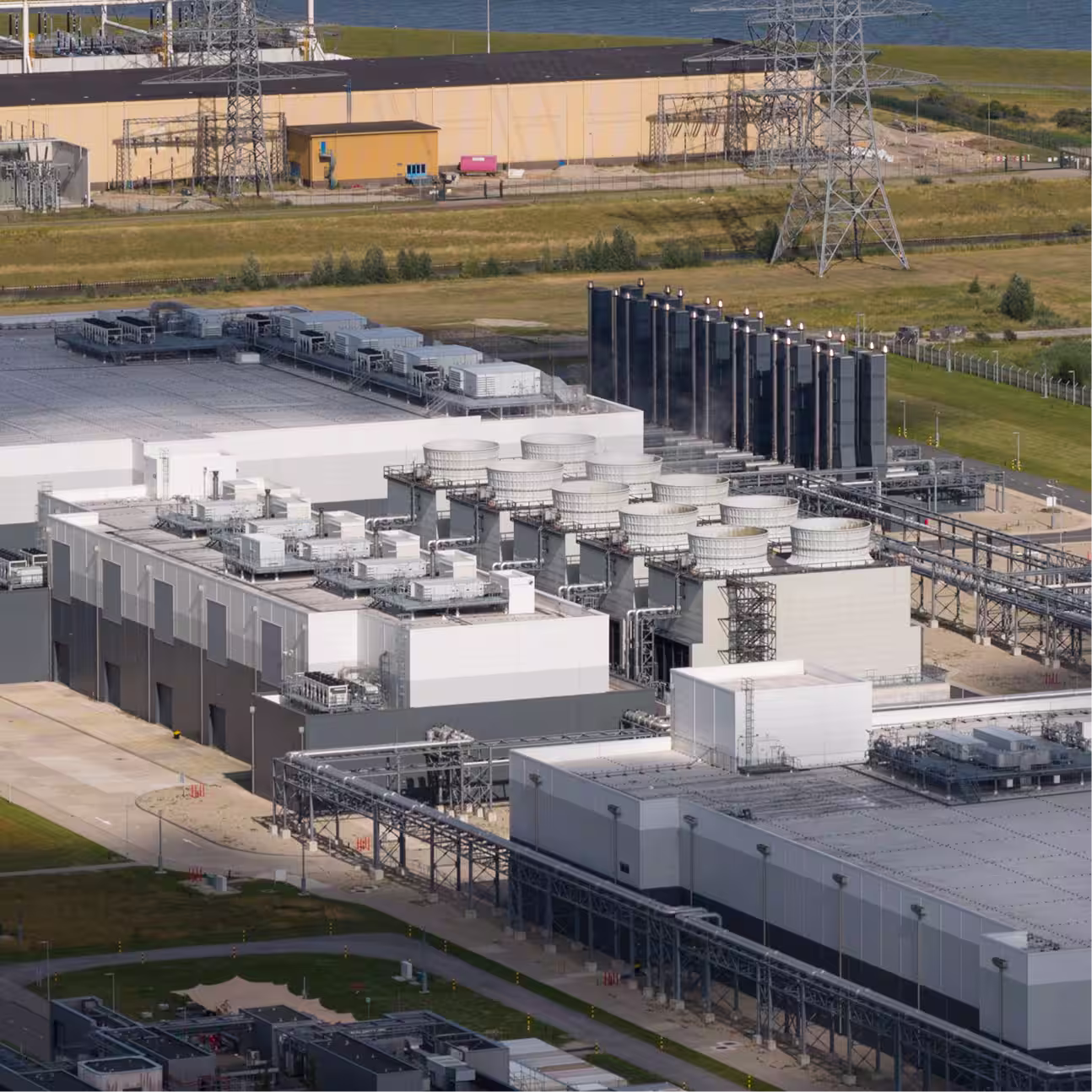 Aerial view of a large Data Center facility with cooling towers, pipelines, and electrical infrastructure.