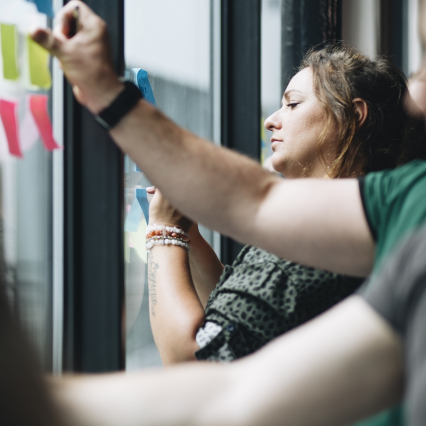 Professional schrijft tijdens een oefening van trainer en coach Amanda Ronhaar van Toer de Werkvloer wat op sticky notes op.