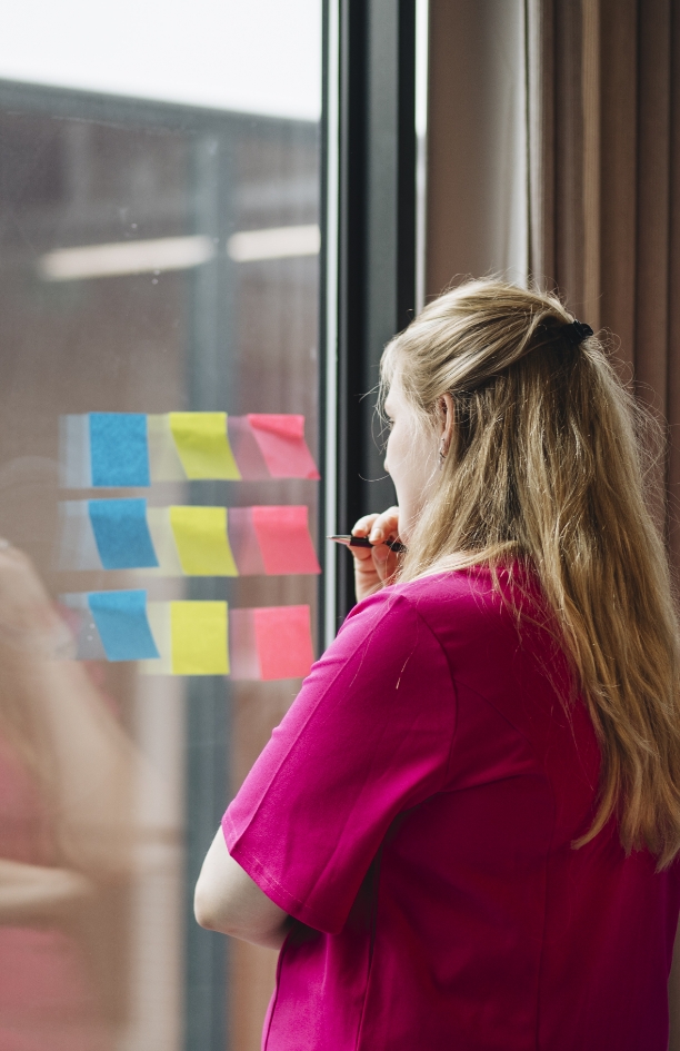 Professional denkt tijdens een training van trainer en coach Amanda Ronhaar na over wat zij op sticky notes wil gaan schrijven.