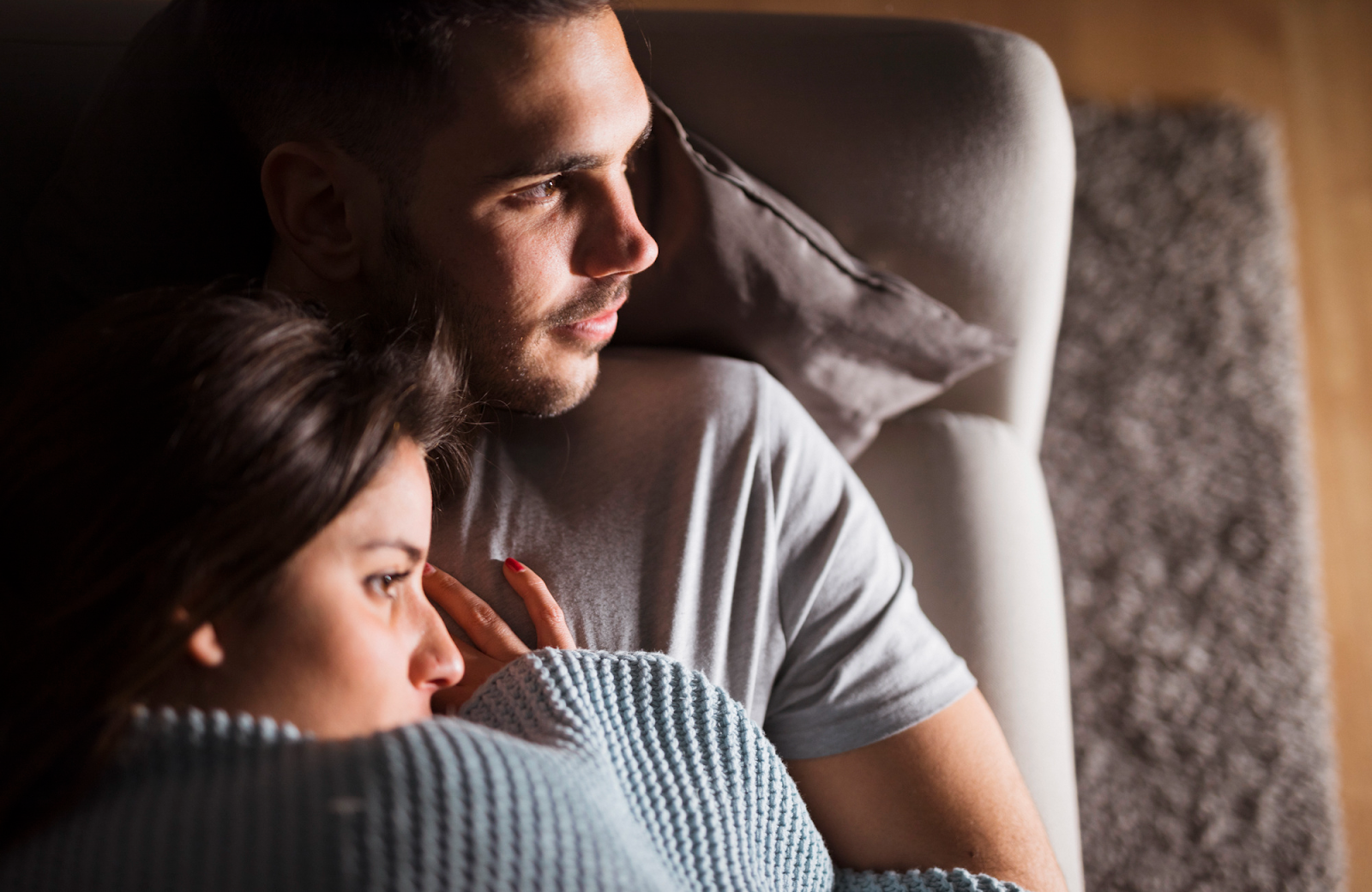 Paar, das auf dem Sofa liegt, beide zur Seite schauend